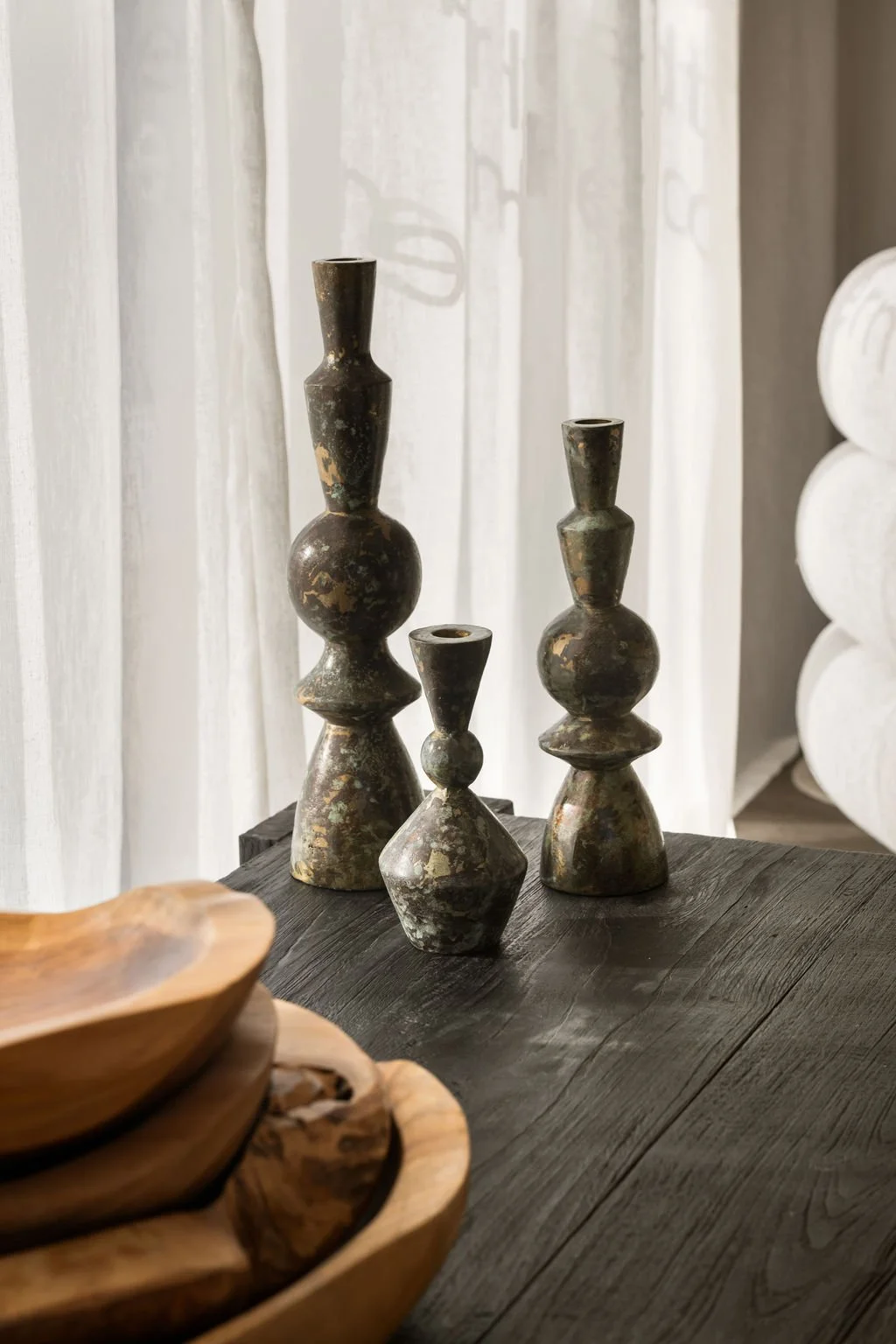 Three decorative vases with geometric shapes and a distressed finish on a dark wooden table.