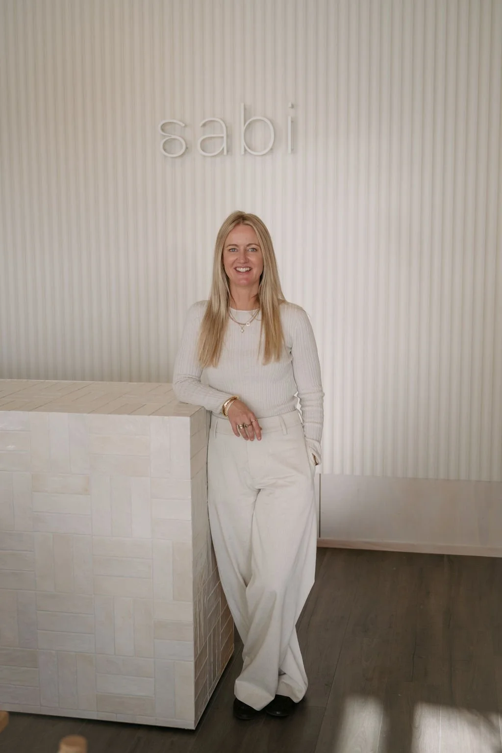 Owner of Wanaka Staging Studio, standing next to a white textured countertop, in front of a wall in her showroom Sabi Living.