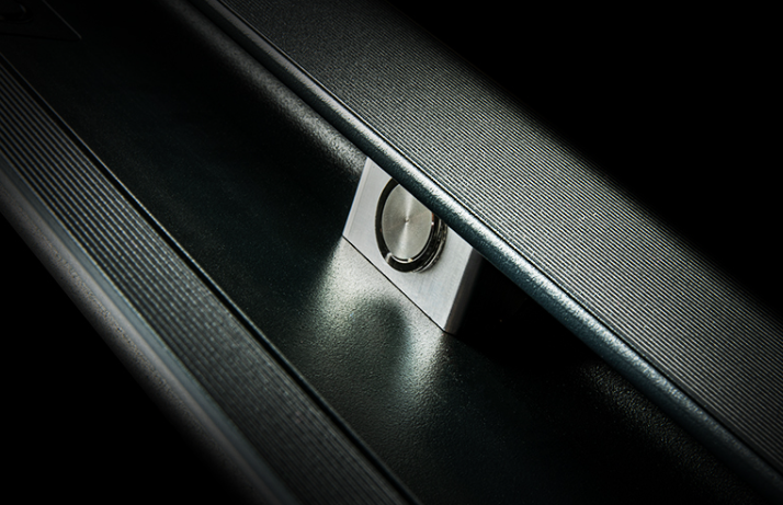 Close-up of a car door lock mechanism with a metallic handle and textured black surface.