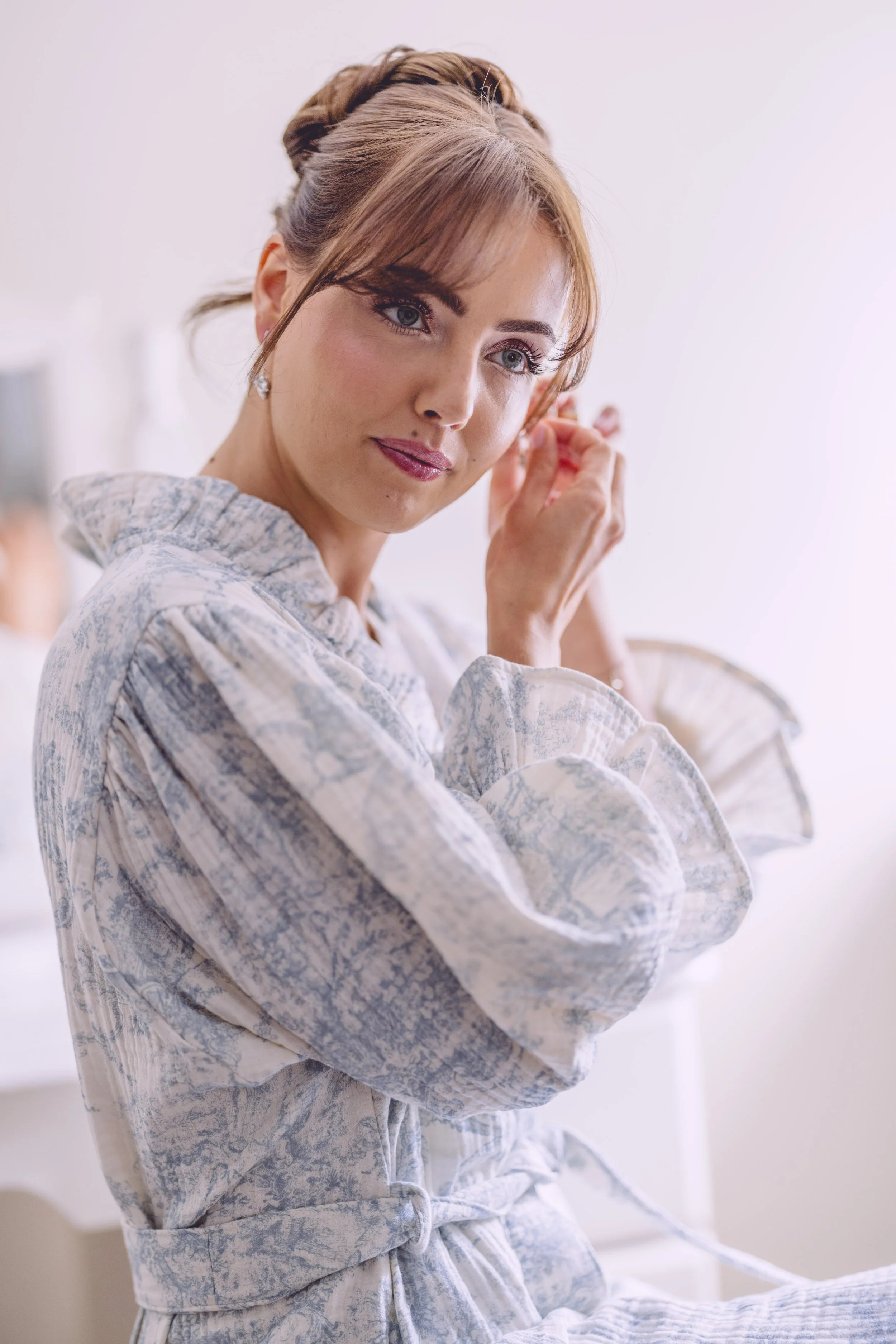 Photo of bride putting on her earring 