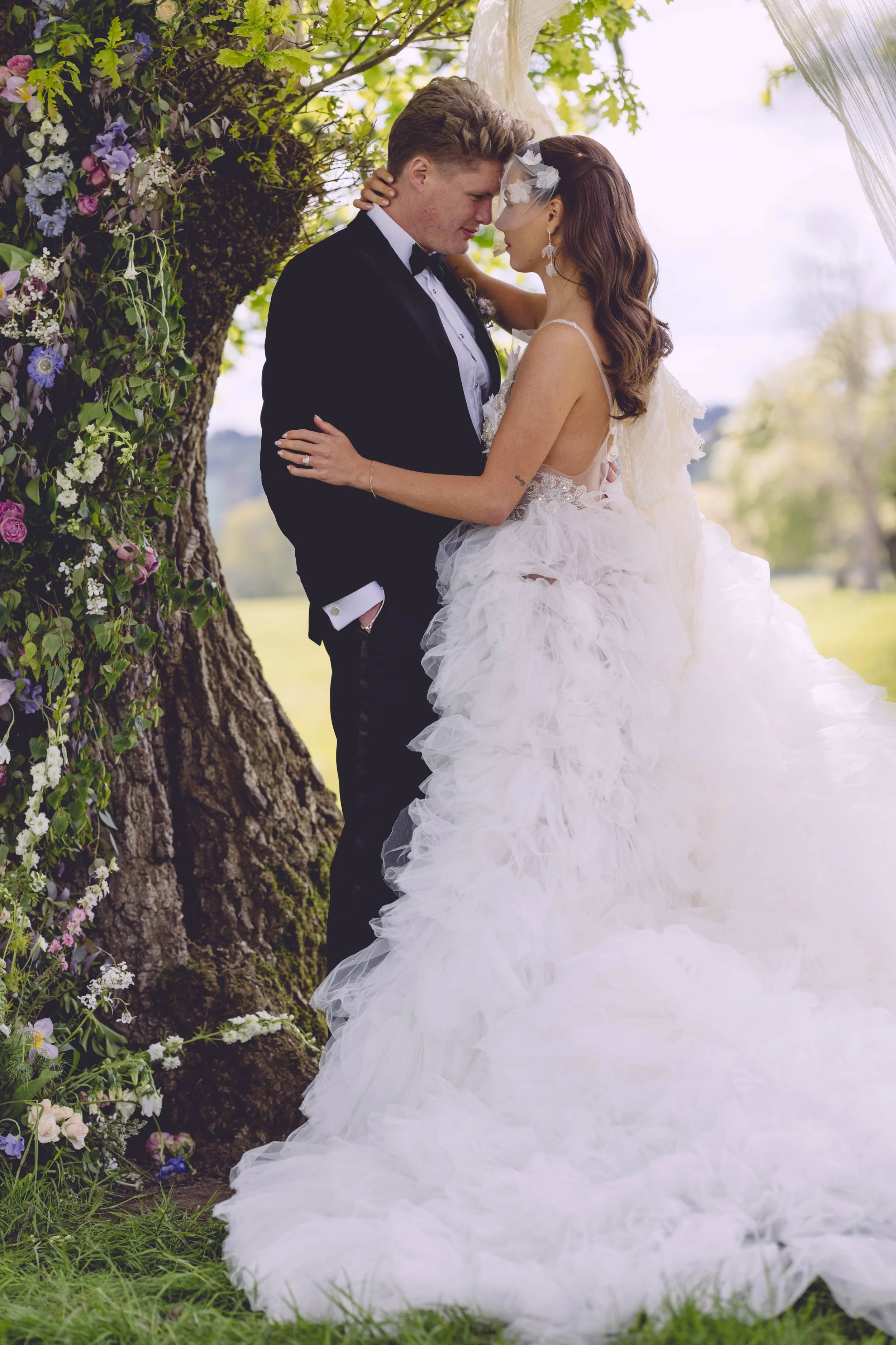 Bride and groom embracing beside oak tree 