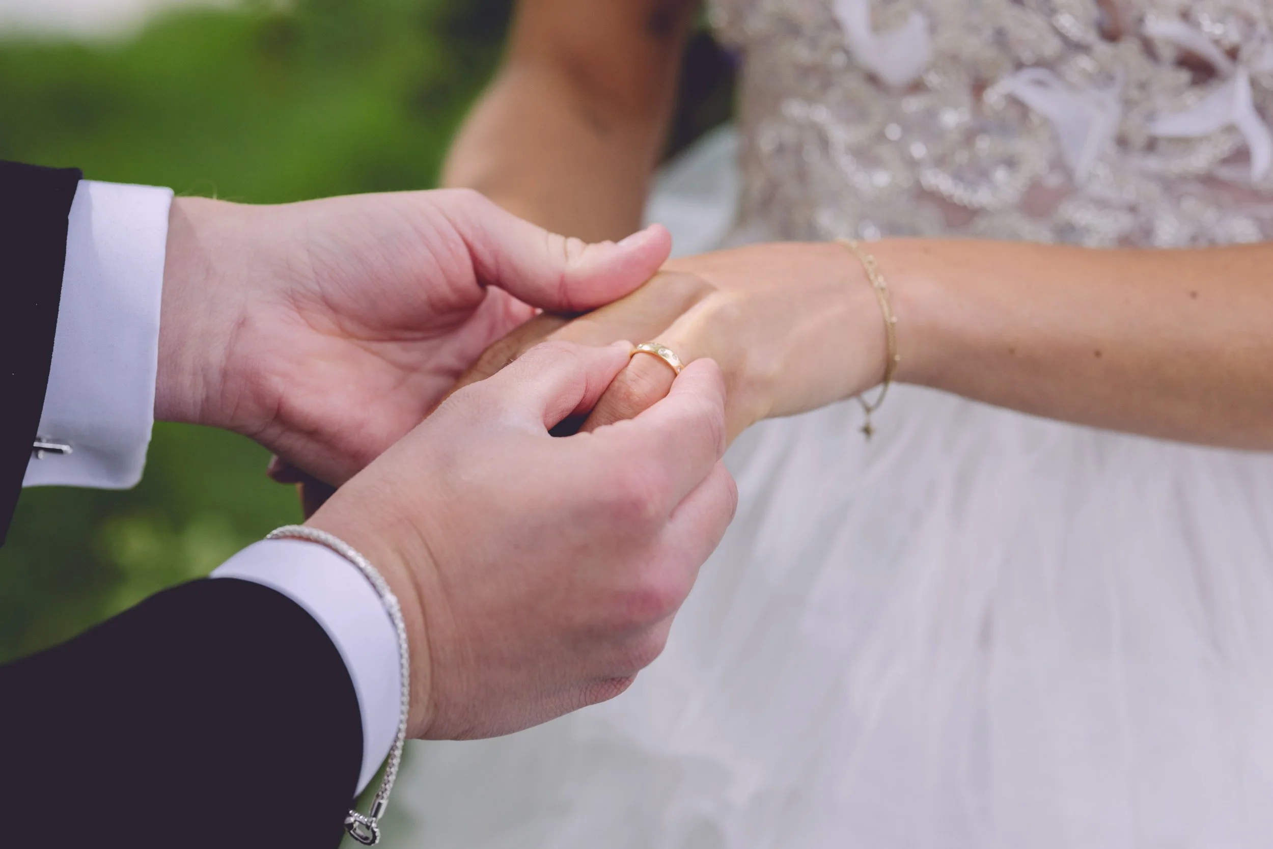 Groom putting on bride's wedding ring