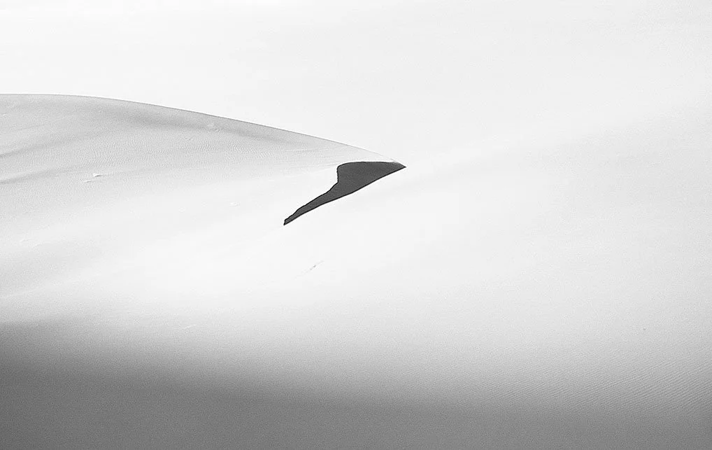 Dunes de sable blanc avec une ombre qui crée un contraste.