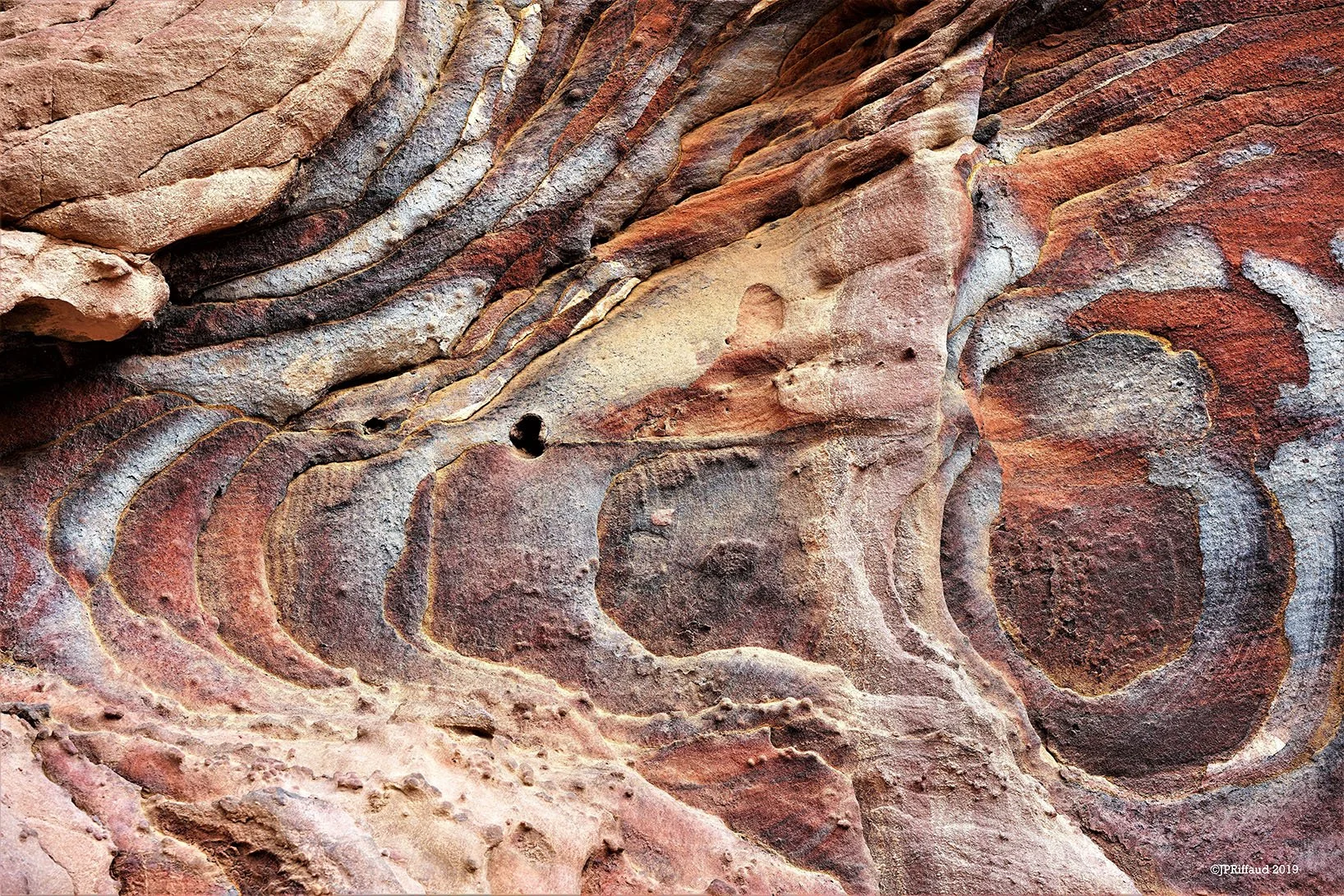 Rochers rouges, marrons et gris avec des stries et des formes naturelles, formations rocheuses dans un canyon.