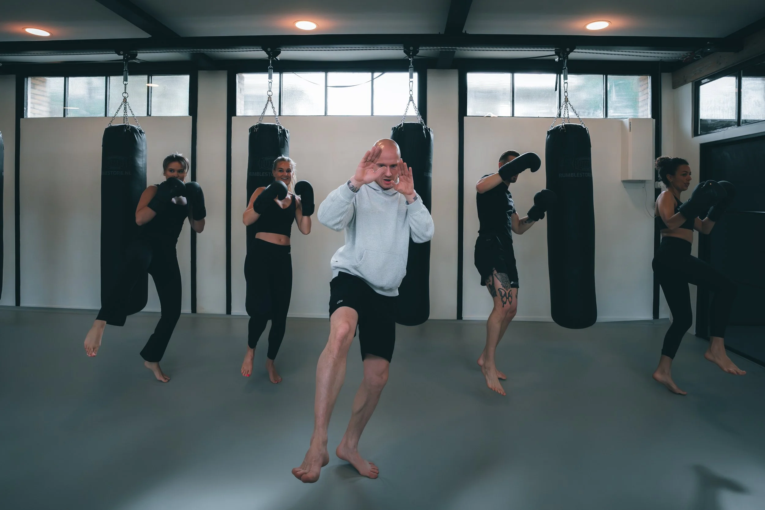Mensen die in een sportschool trainen, met enkele mensen die bokshandschoenen dragen en een man die in het midden oefent.