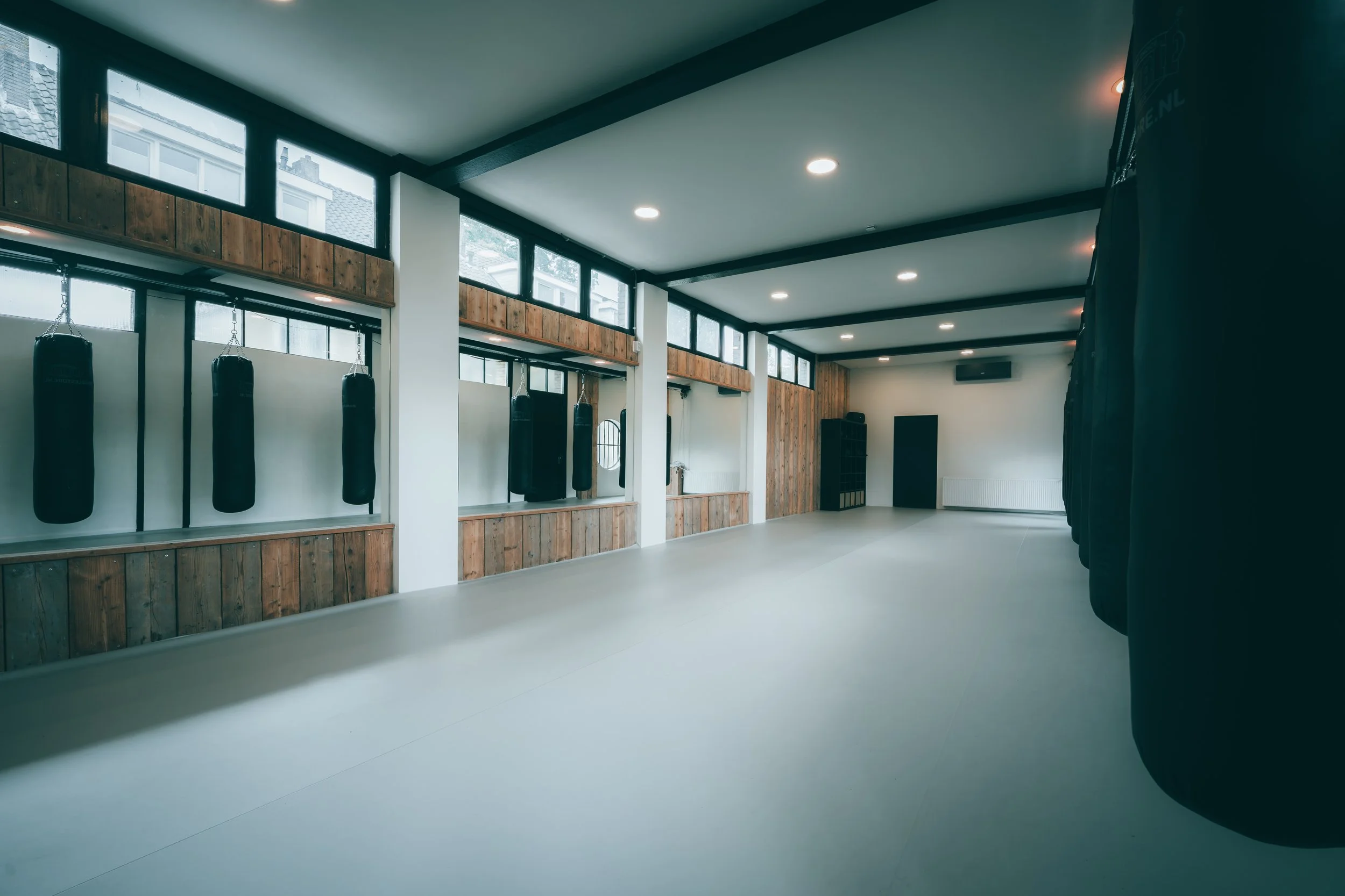 Binnenruimte van een sportschool met trainingskussens en houten bekleding aan de wanden.
