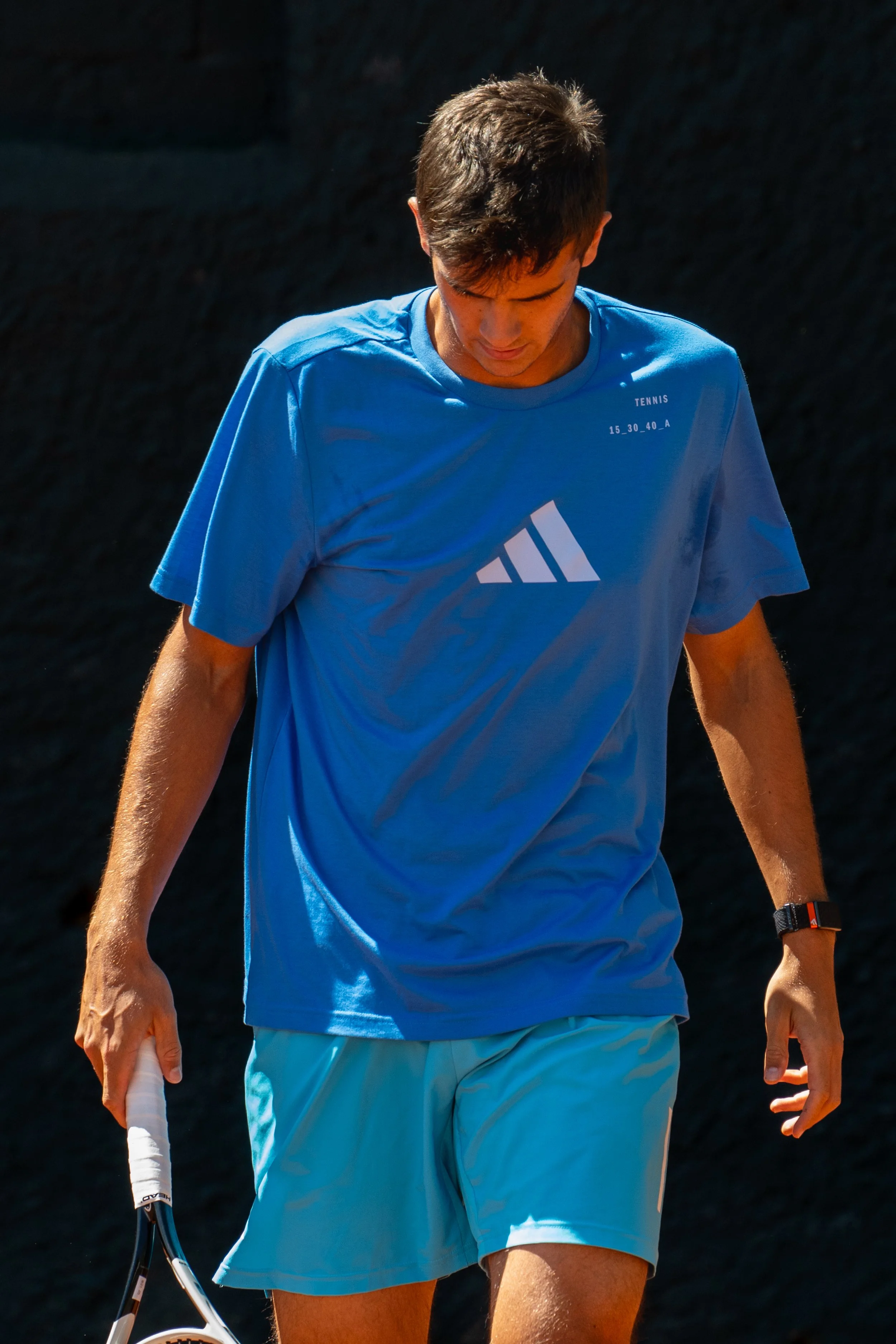 Rafael Jodar in a blue shirt and shorts, holding a tennis racket, walking outdoors at the Barcelona Open, Spain.