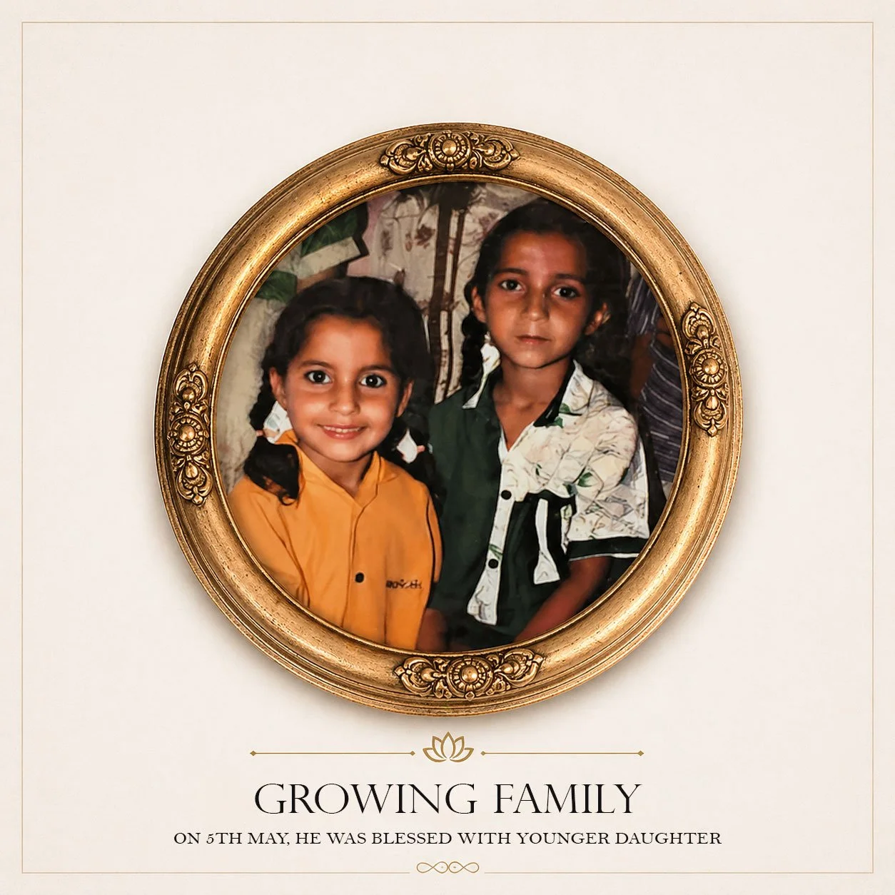 A framed photograph of two young girls smiling, one with pigtails wearing an orange shirt and the other with braided hair wearing a patterned shirt. The frame is ornate and gold-colored. The image is accompanied by the text "Growing Family" and a note indicating it was taken on May 5th, when a man was blessed with a younger daughter.