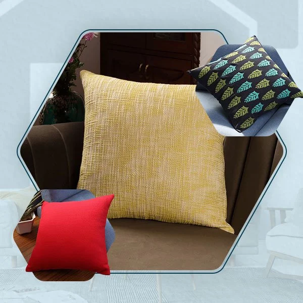A large yellow textured throw pillow, a smaller red pillow, and a navy pillow with a green leaf pattern on a brown sofa.