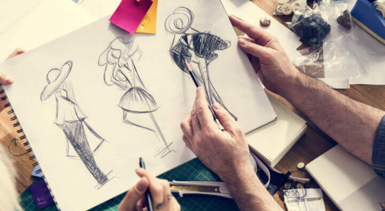 Person sketching fashion design sketches of dresses on paper.