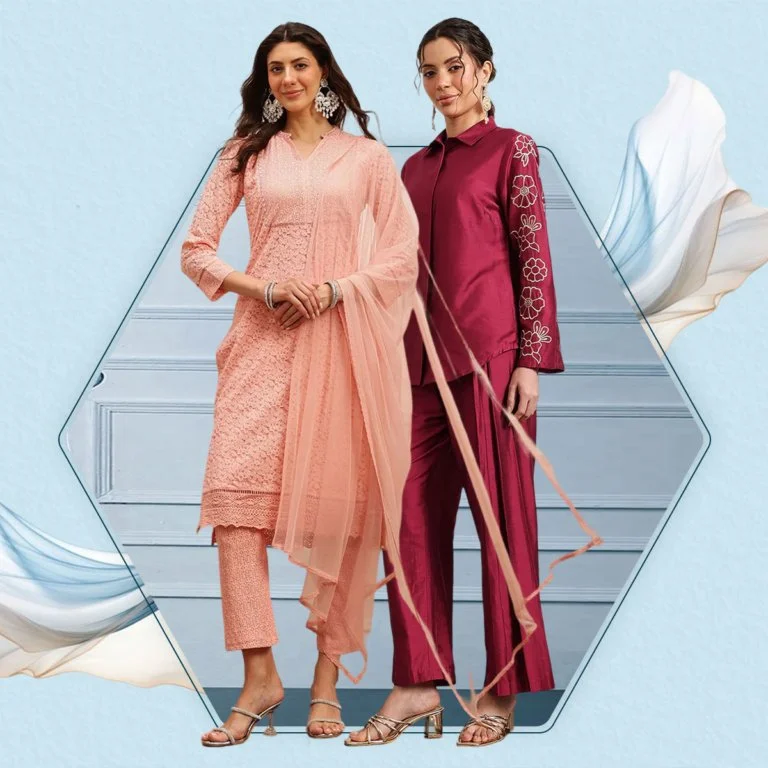 Two women standing side by side against a blue wall, dressed in traditional South Asian attire. One woman is wearing a pink and peach embroidered outfit, and the other is wearing a deep pink, maroon, or burgundy outfit with floral embroidery on the sleeves.