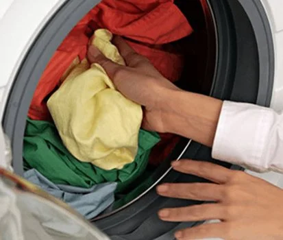 Person inserting laundry into washing machine.