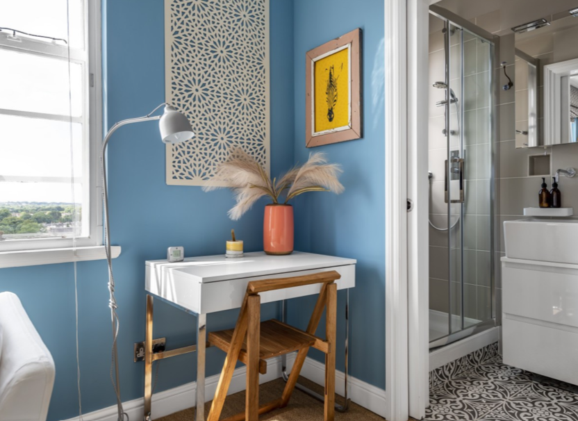 Blauwe hoek in de gastenkamer met bureau, lamp en eigen doucheruimte