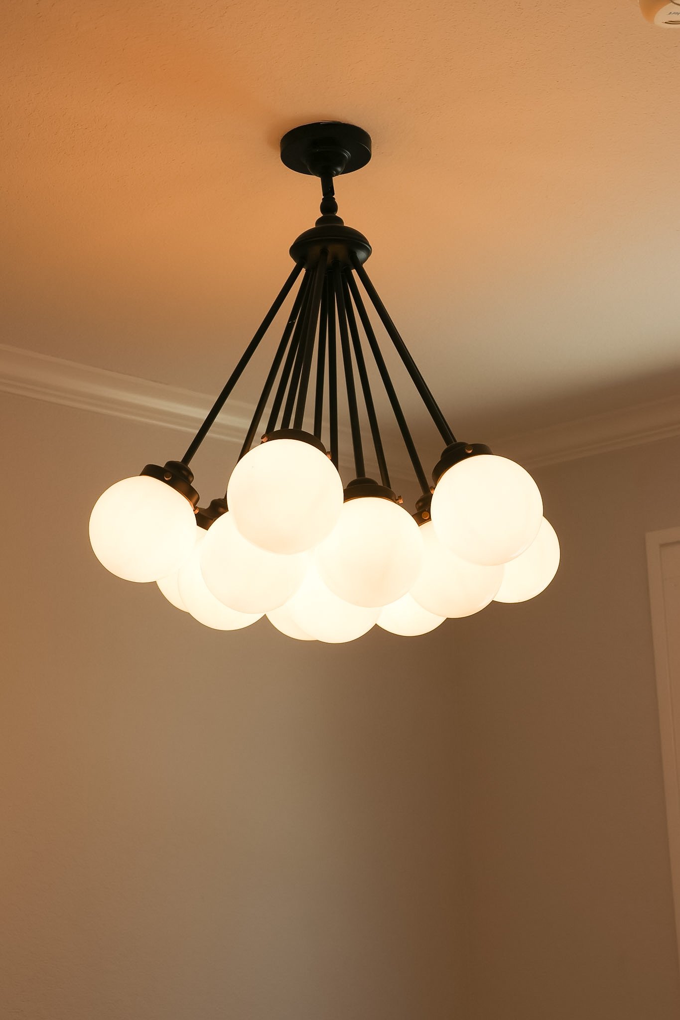 A chandelier with multiple white globe-shaped lights hanging from black rods.