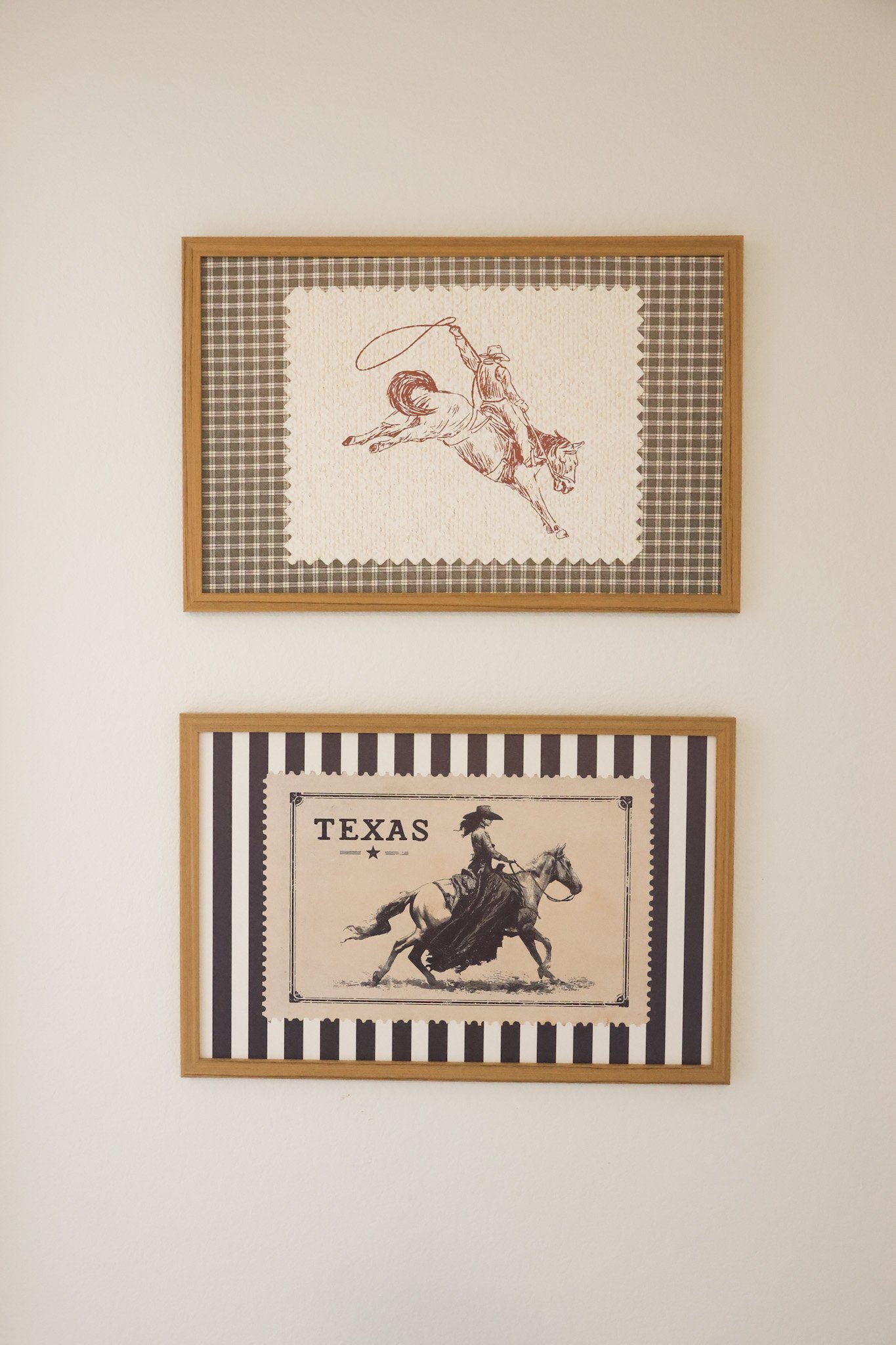 Two framed prints on a white wall, one with a cowboy on a bucking horse and the other with a cowboy riding a horse in a western scene.