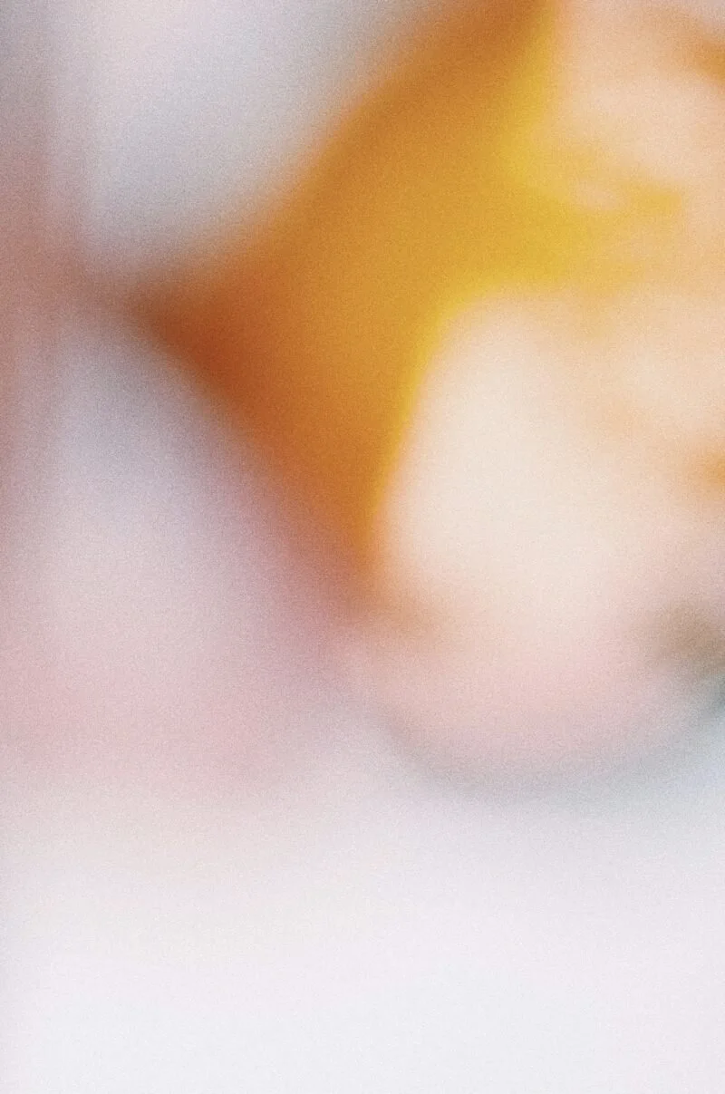 Blurred close-up of a yellow object on a white and pink background.