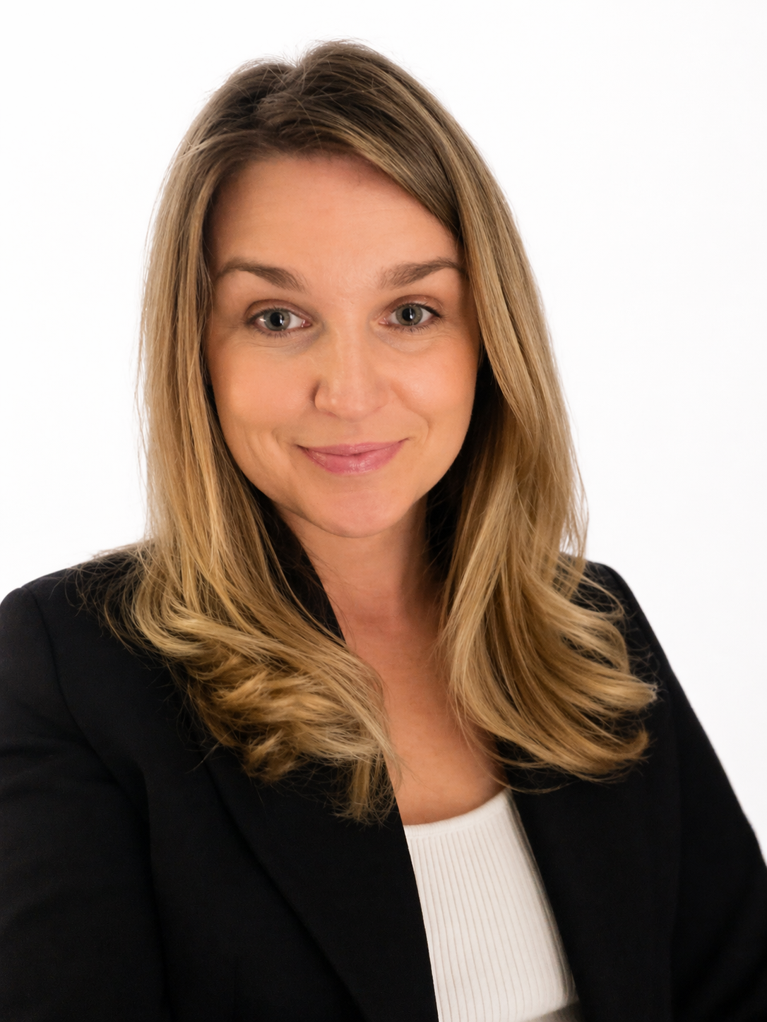 A woman with shoulder length light brown hair, wearing a black blazer and white top, smiling with neutral background.