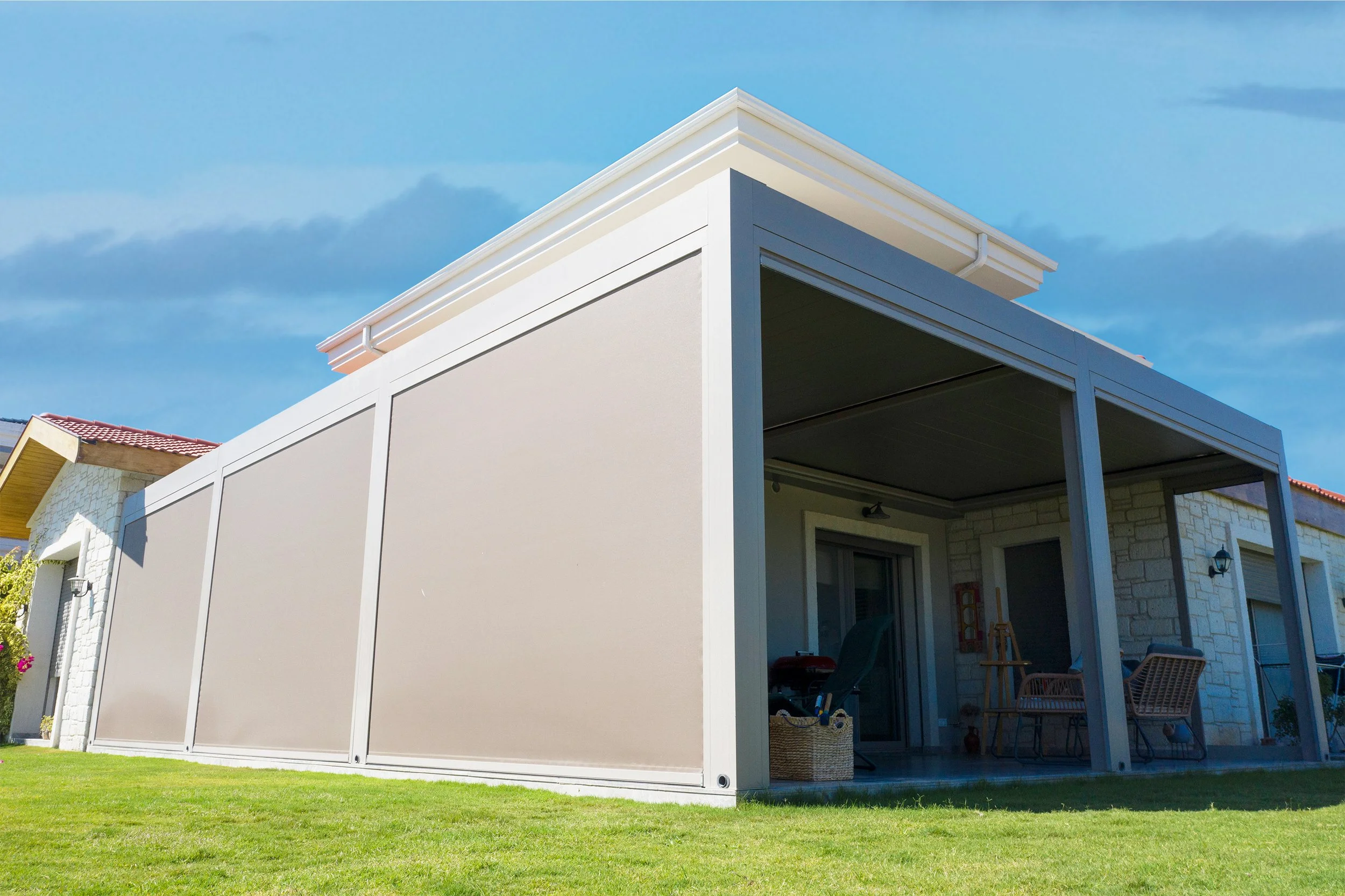 Haus mit moderner verglaster Terrasse und grünem Rasen, blauer Himmel