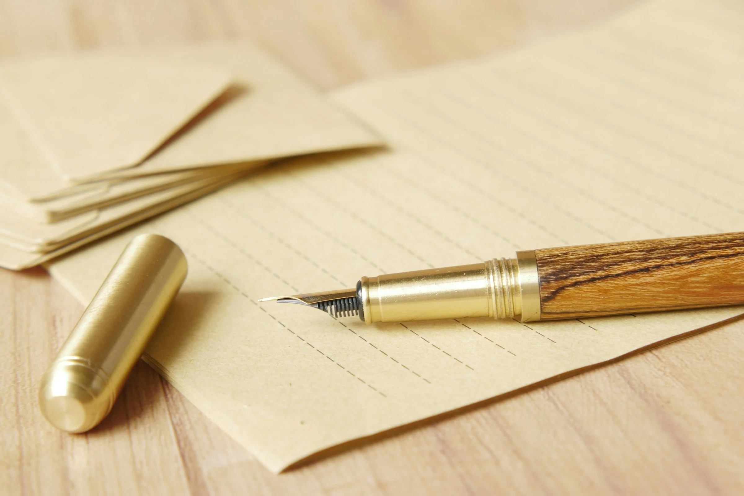 Fountain pen resting on cream paper on a warm wood desk