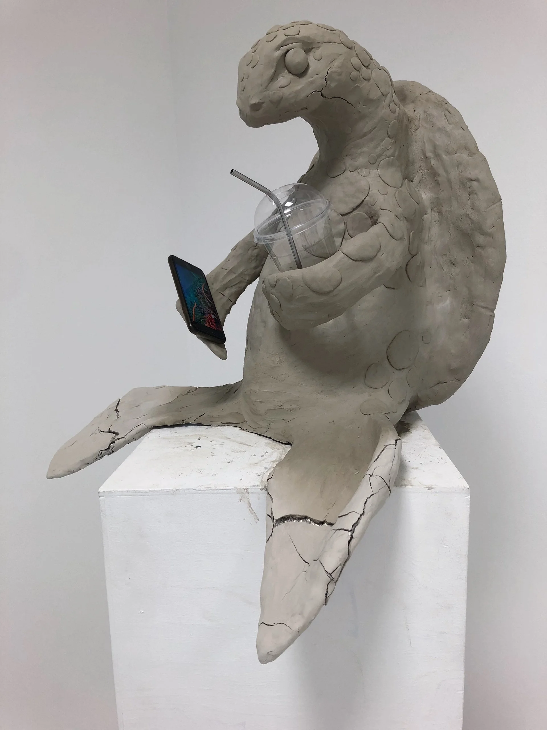 En skulptur av en skilpadde laget av hvitt materiale, som holder en plastikk kopp, telefon og sugerør. Konseptkunst Konseptuelle arbeider. Konsept.