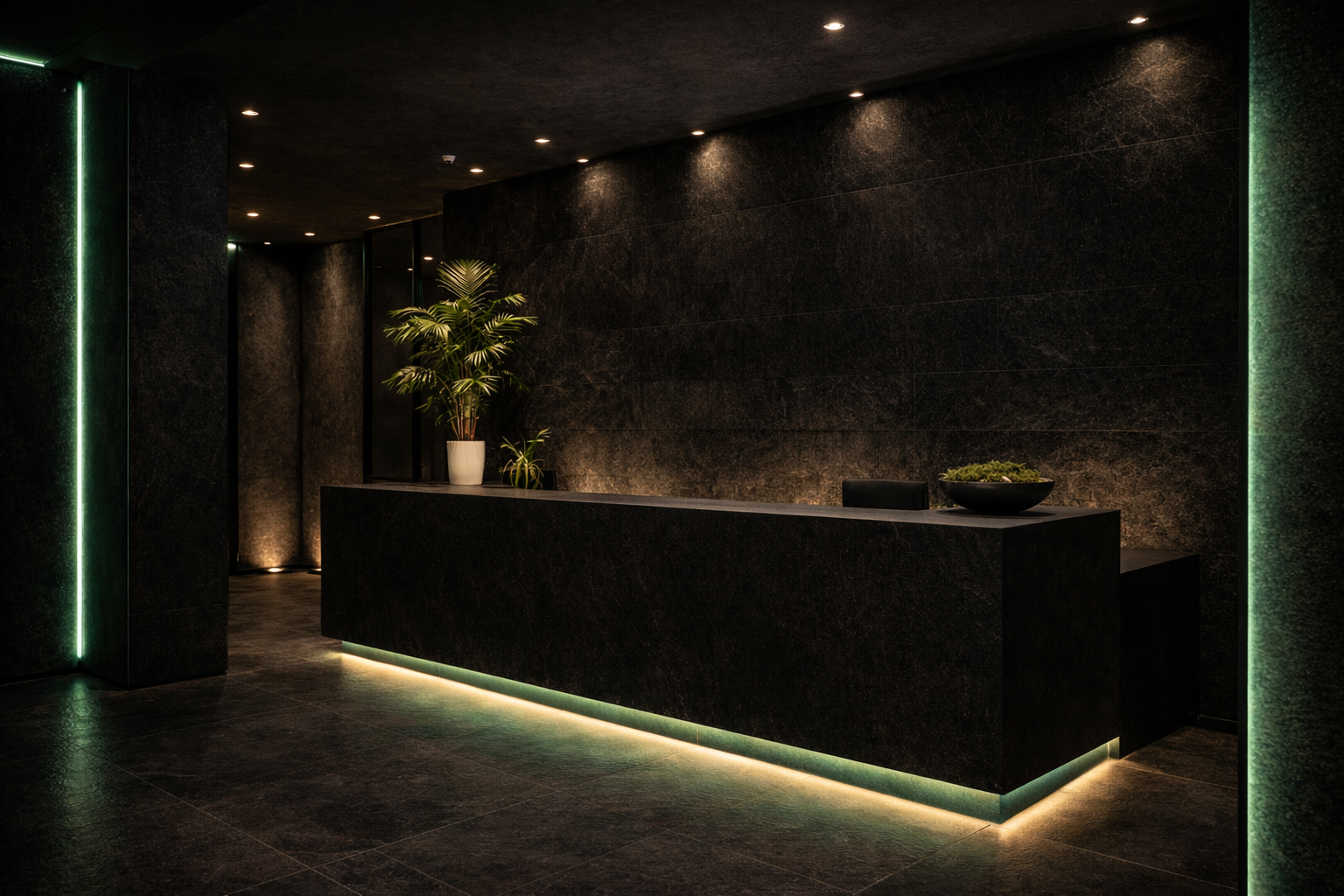 Modern hotel lobby reception desk with a black stone finish, illuminated by soft green lighting, and decorated with potted plants.