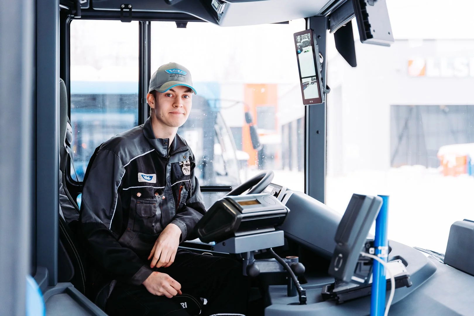 VDL bussien kuvapankki valokuvaus. Huolto henkilö istuu bussin kuljettajan istuimella.