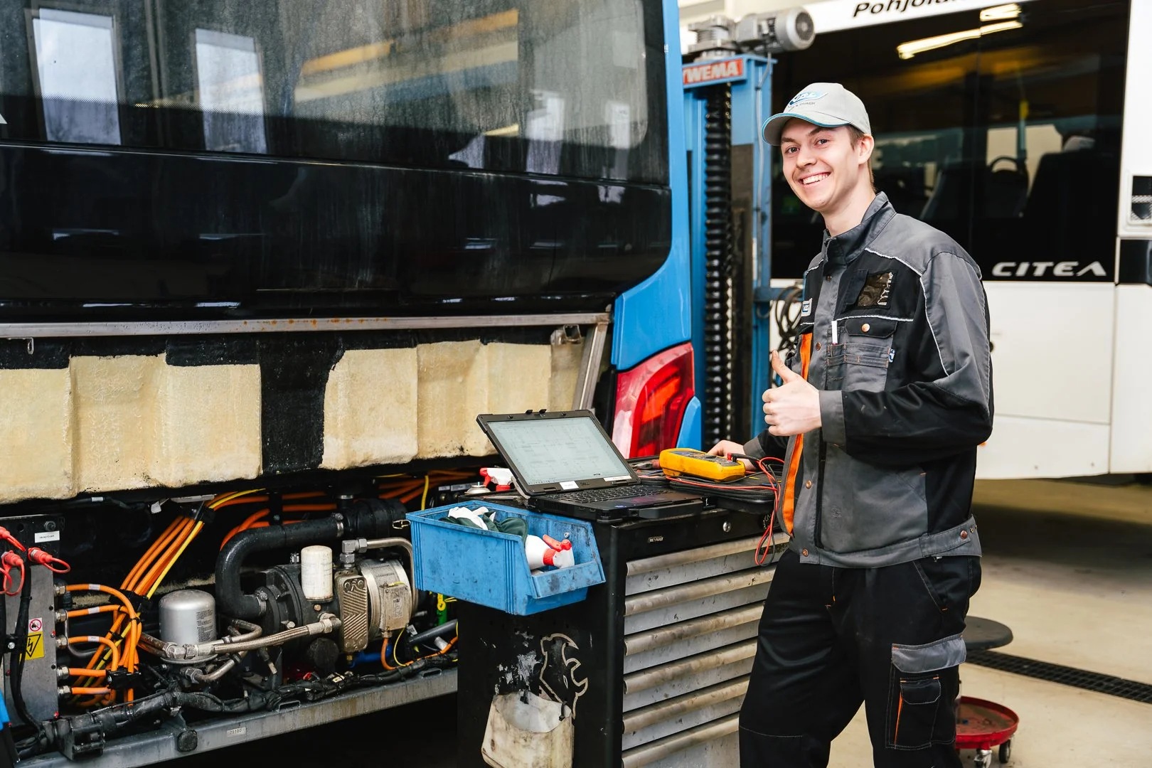 VDL bussien kuvapankki valokuvaus. Mekaanikko huoltaa bussia käyttäen tietokonetta.
