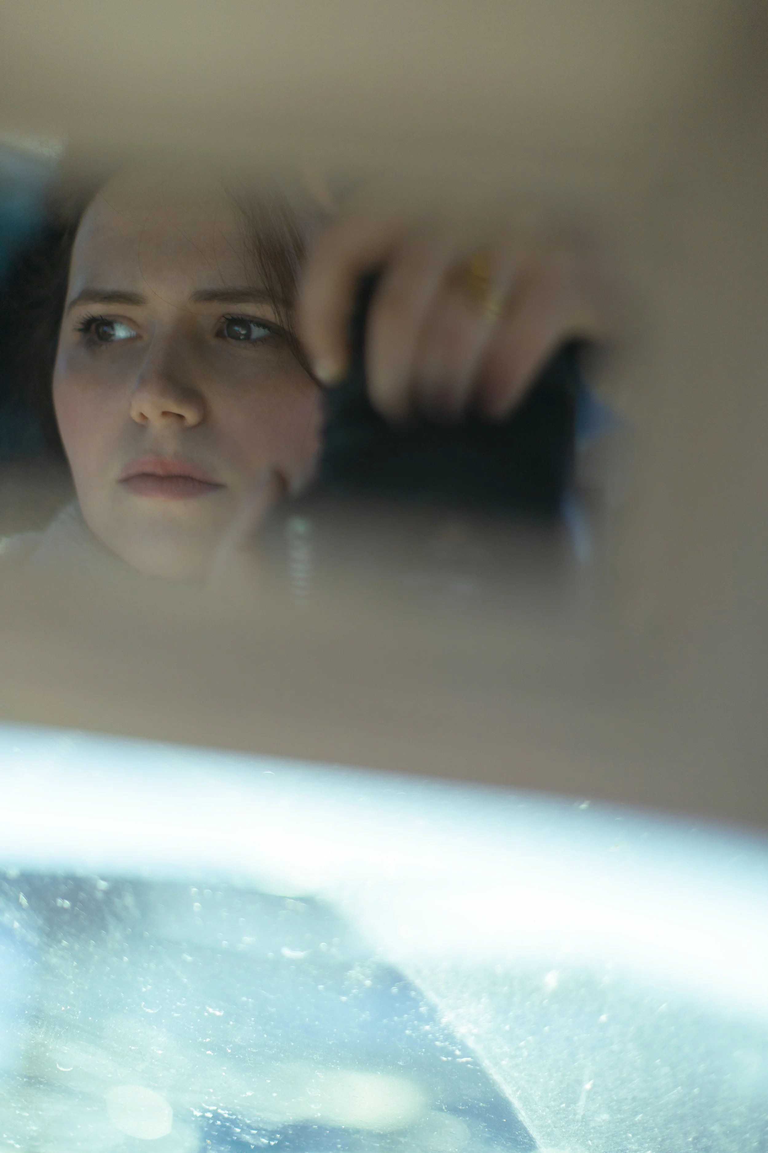 Une femme regarde dans un miroir, sa réflexion est visible, avec un focus sur son visage et ses yeux.