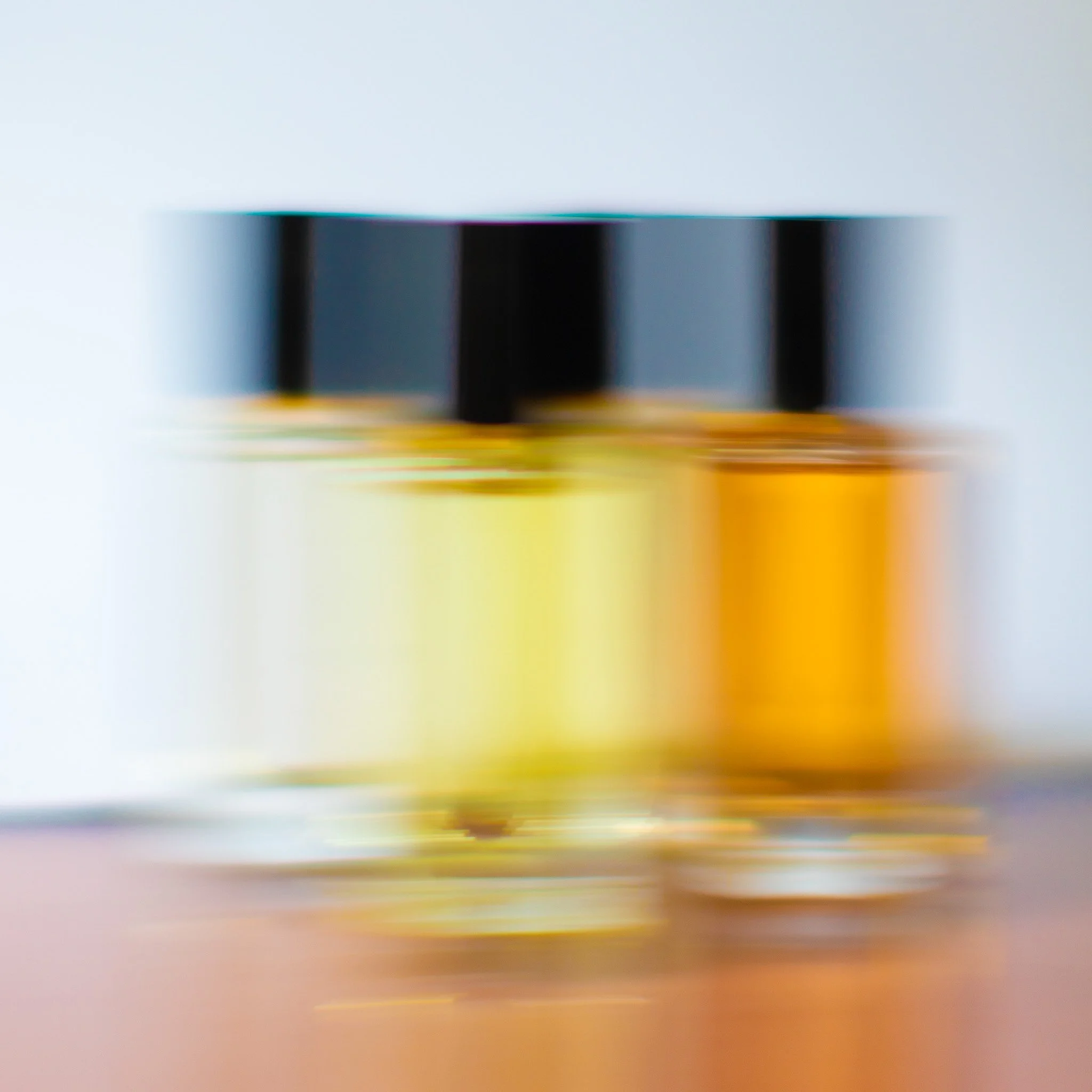 Bouteilles de parfums avec couvercles noirs sur une surface en bois, flou artistique.