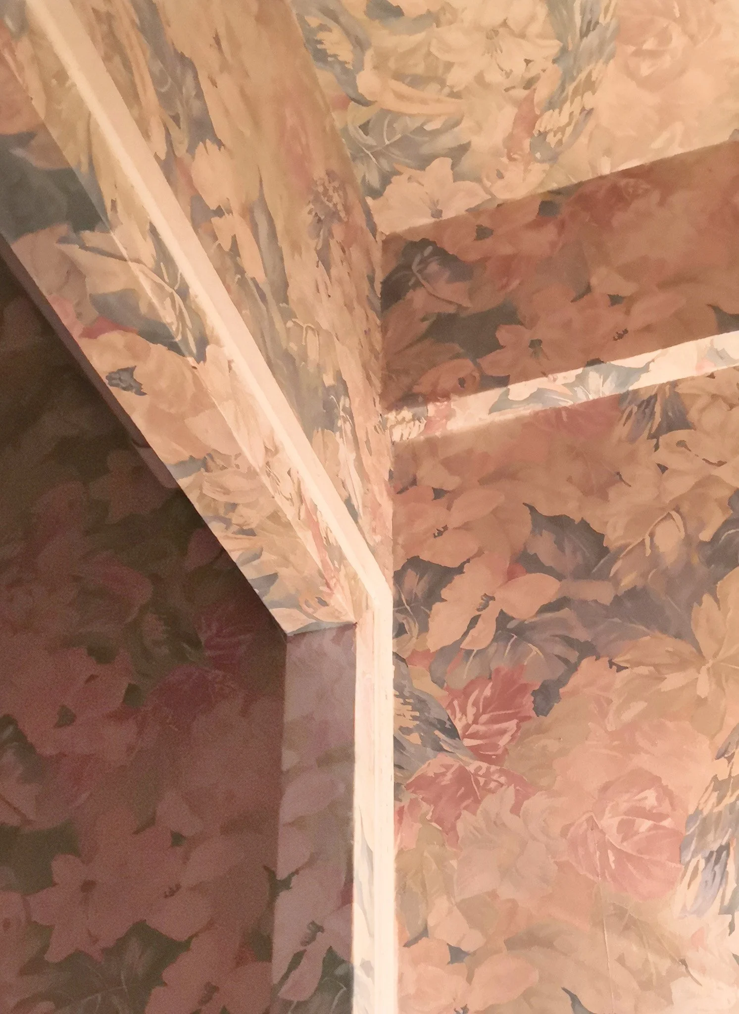 Coin intérieur avec murs et plafond recouverts de papier peint à motif de feuillages aux couleurs automnales.