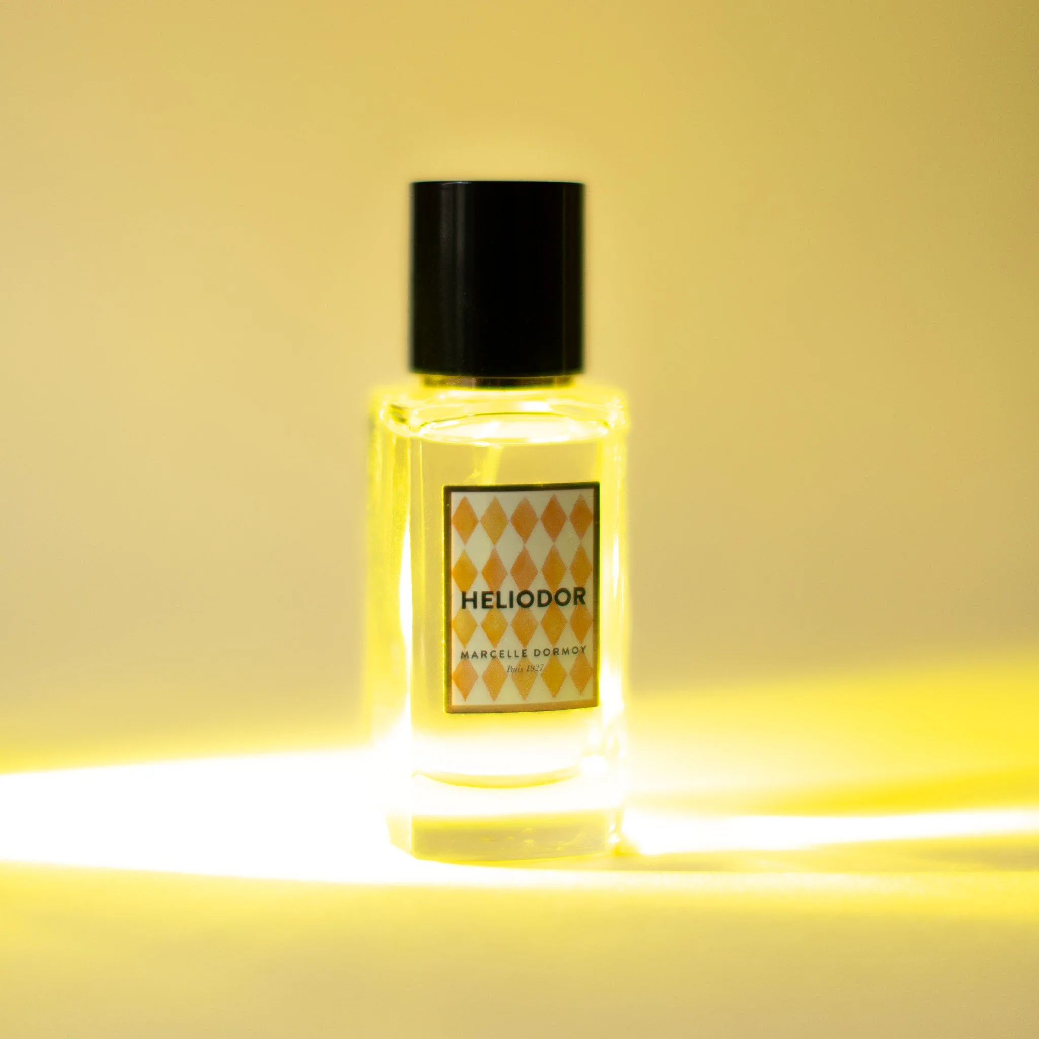 Bouteille de parfum appelée Heliador par Marcelle Dormoy, avec un fond jaune lumineux.