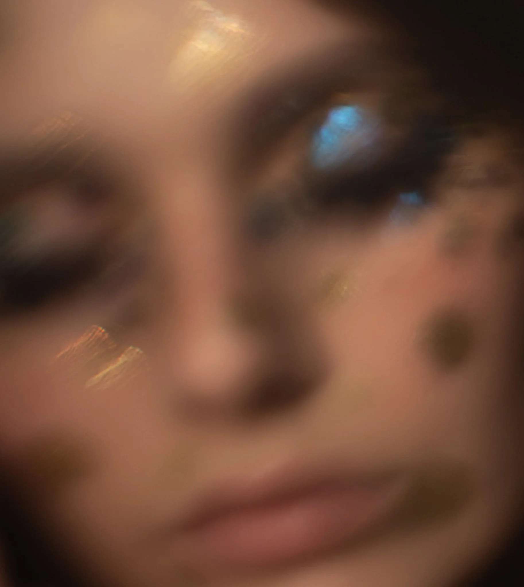 Premier plan flou d'un visage humain de près, avec une attention sur un œil.