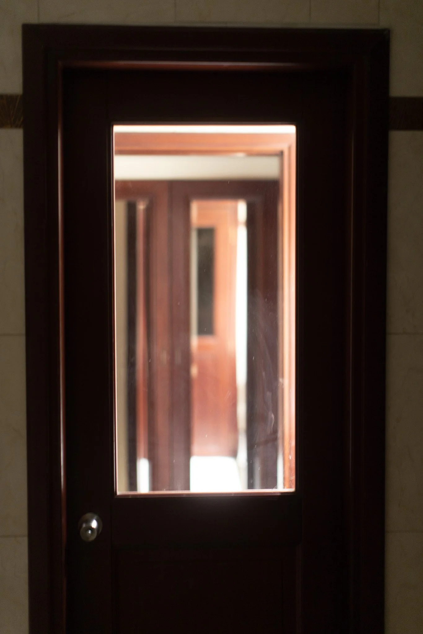 Portes en verre avec cadre en bois, avec des reflets dans la vitre, montrant des portes similaires en arrière-plan.