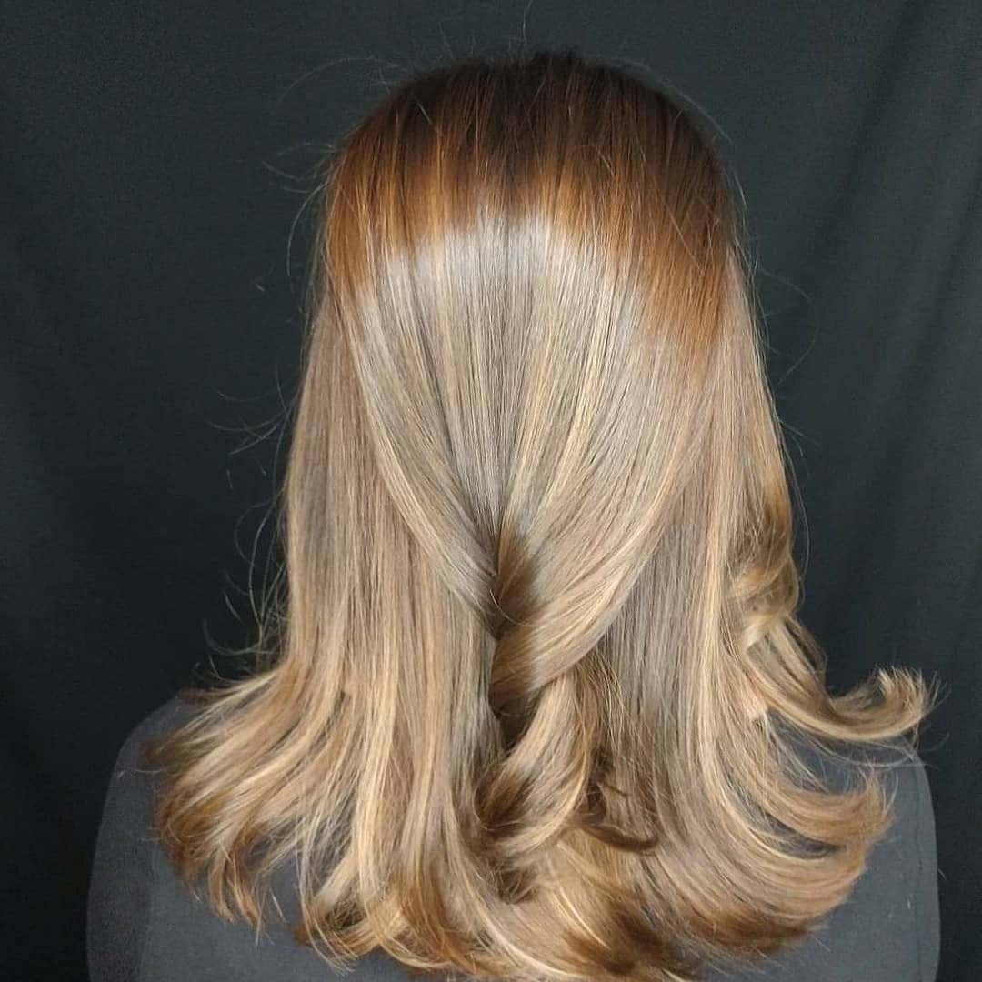 Back view of a woman's shoulder-length blonde hair with loose curls, against a black background.