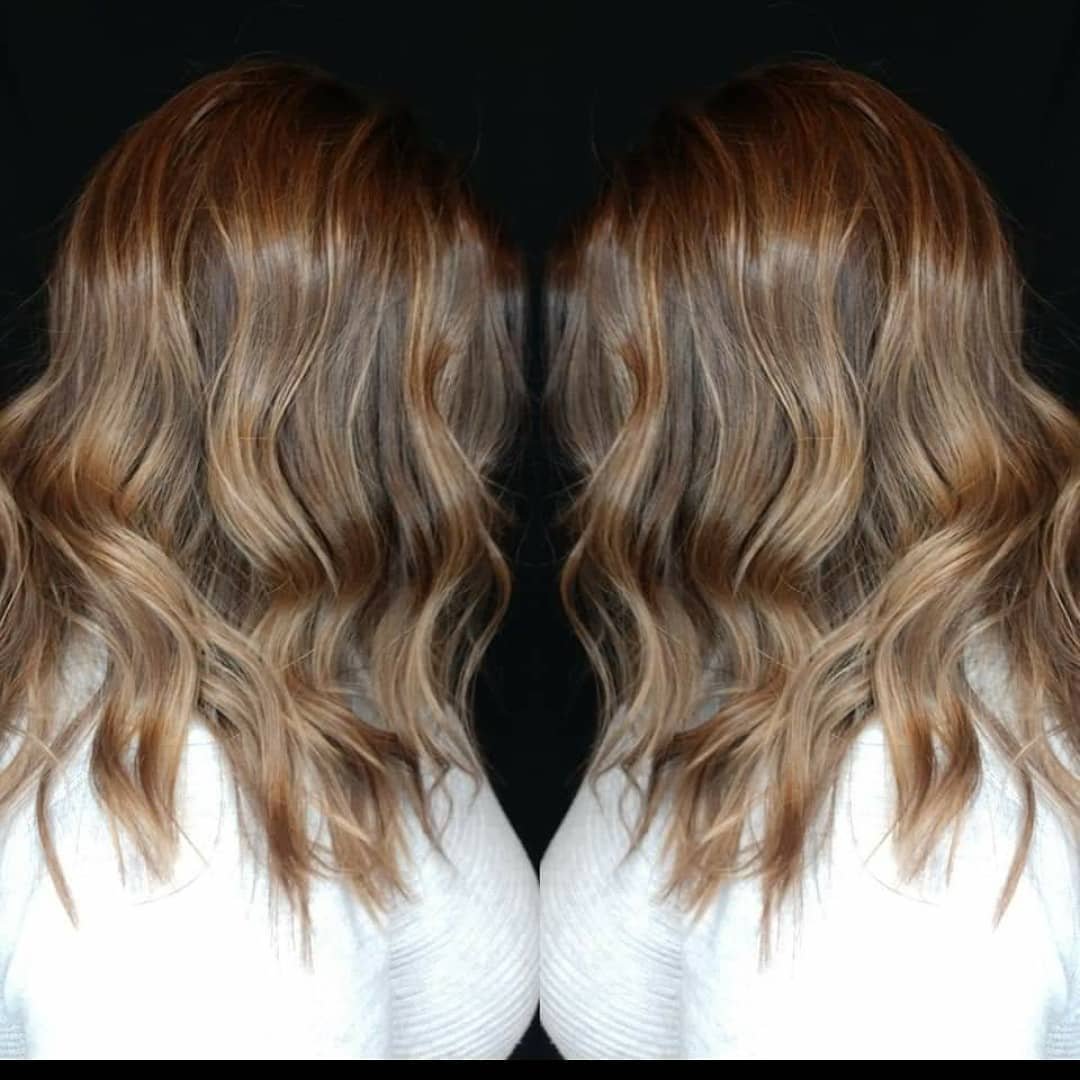 A mirrored image of wavy, blonde hair against a black background, with the person wearing a white top.