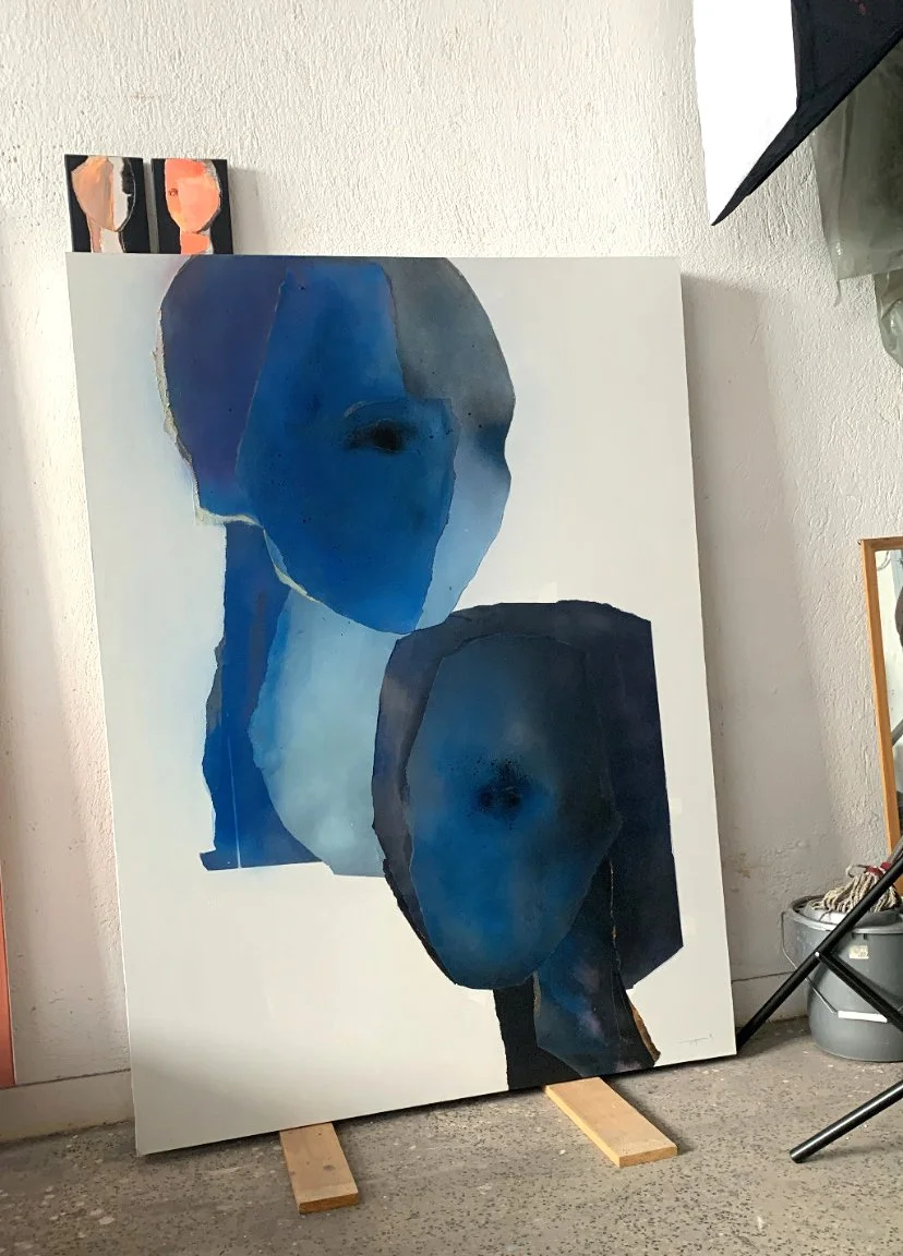 Abstract painting of two human faces in shades of blue and black on a white canvas.