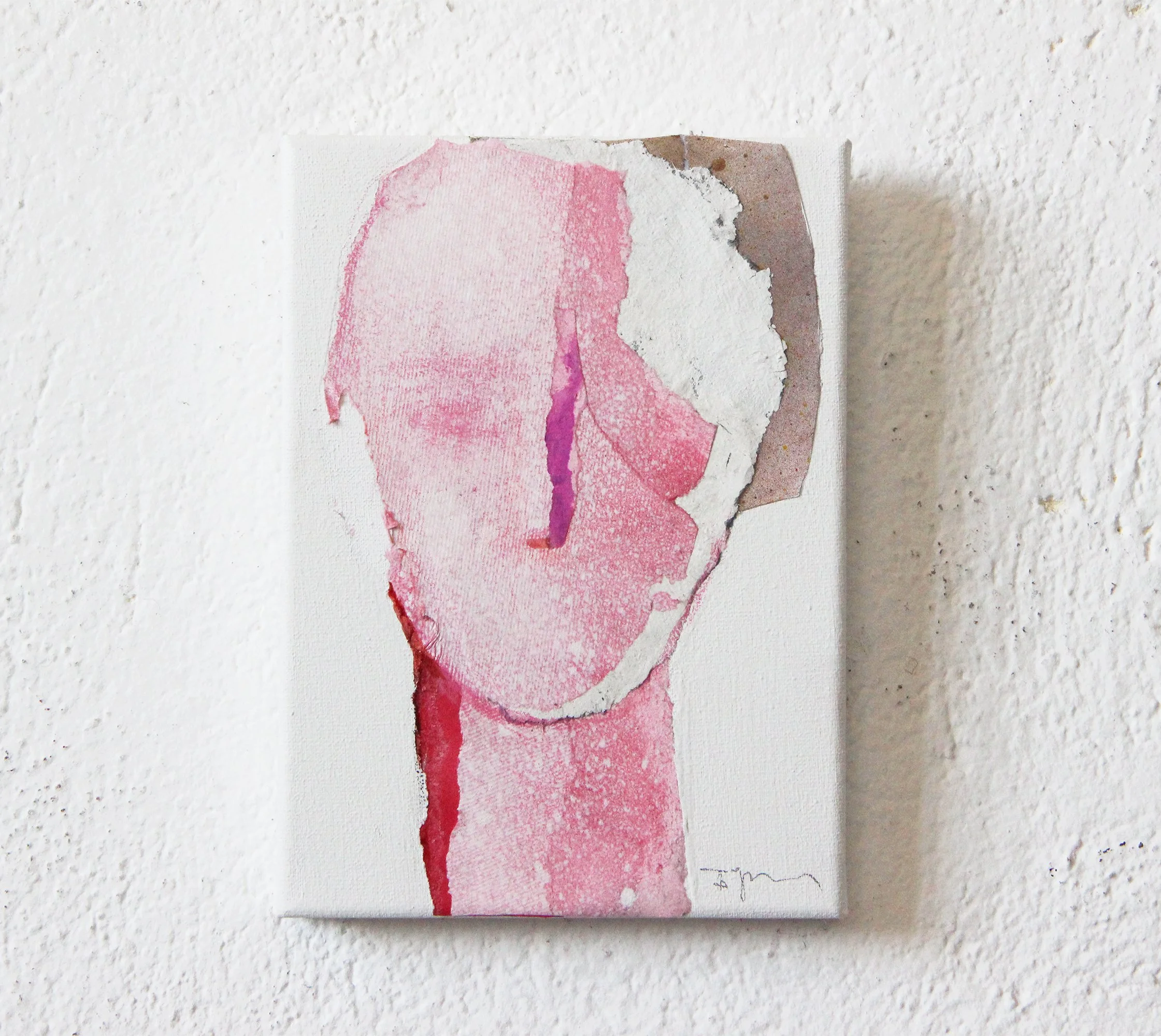 Mixed media abstract art portrait of a person with a torn, layered look, predominantly in pink, purple, and white tones, mounted on a white wall.