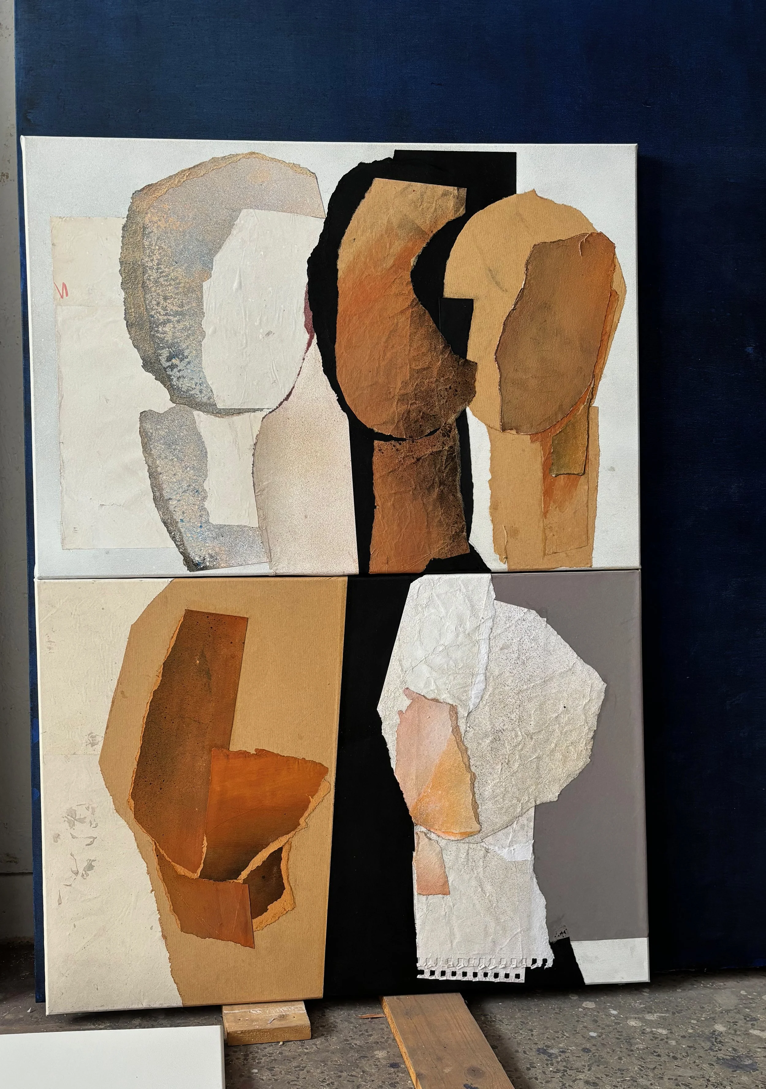 Abstract split canvas painting of female faces using torn paper and textured materials in neutral tones on a wood surface.