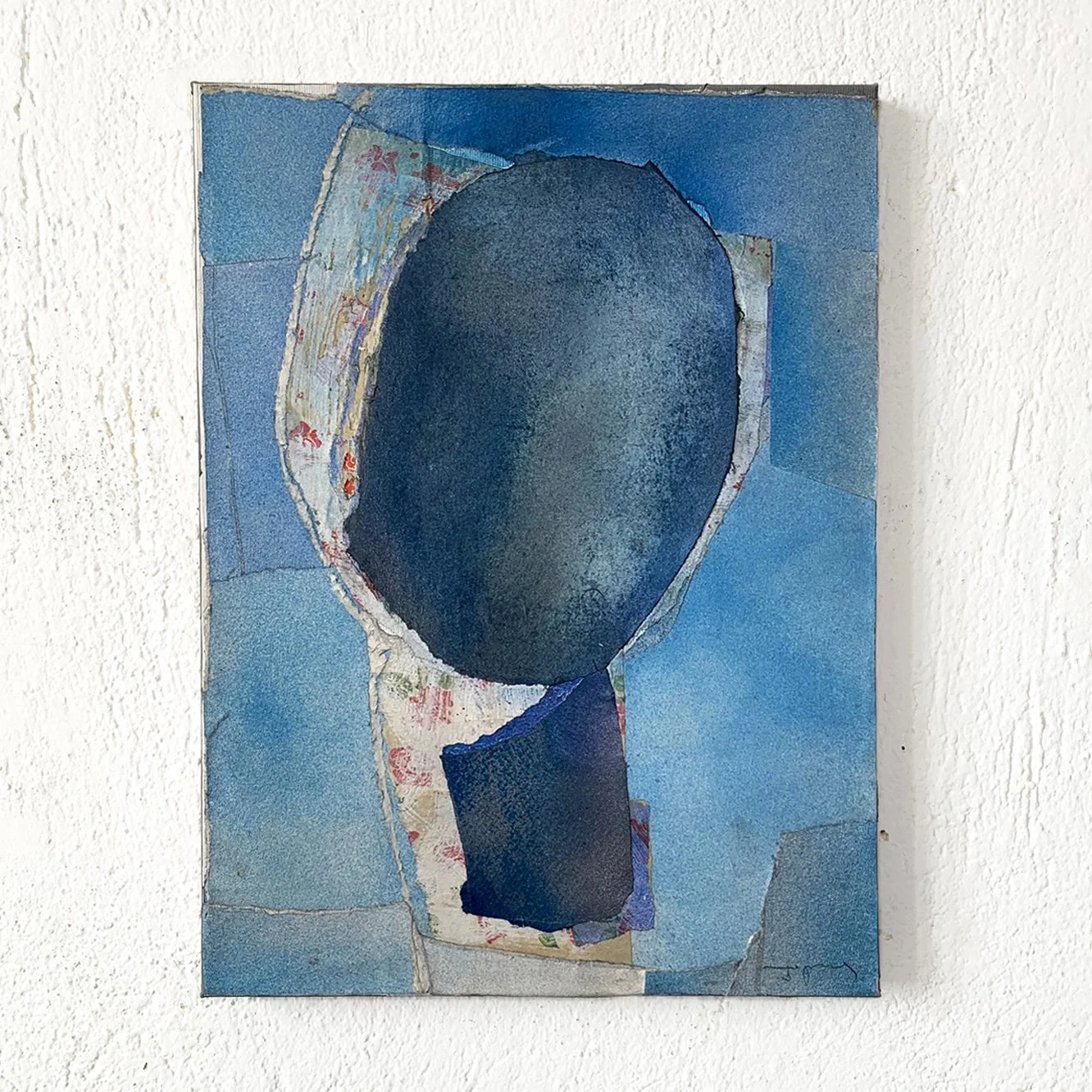Abstract painting featuring shades of blue with a central dark oval shape and layered torn paper textures.