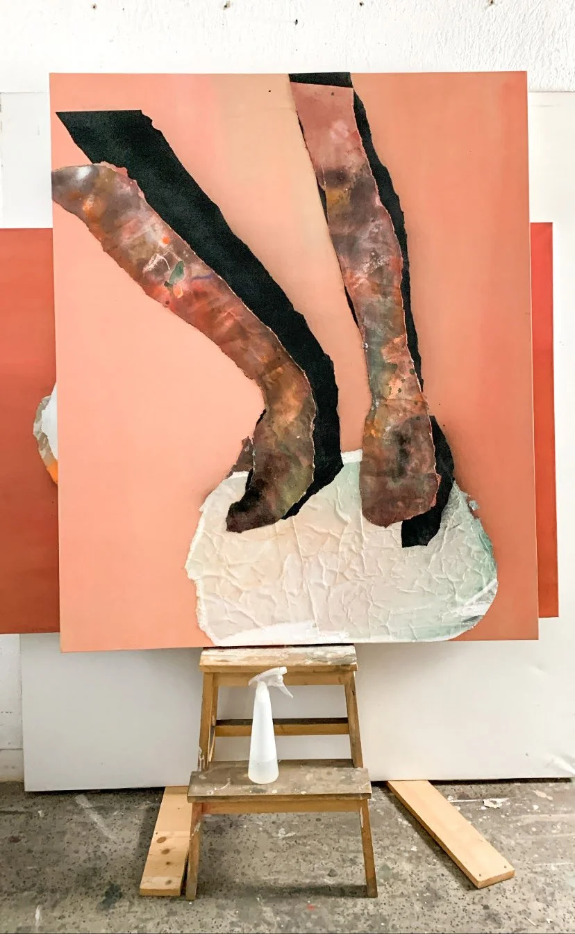 Abstract mixed media artwork on canvas with torn paper and paint, placed on a wooden easel in an artist's studio.