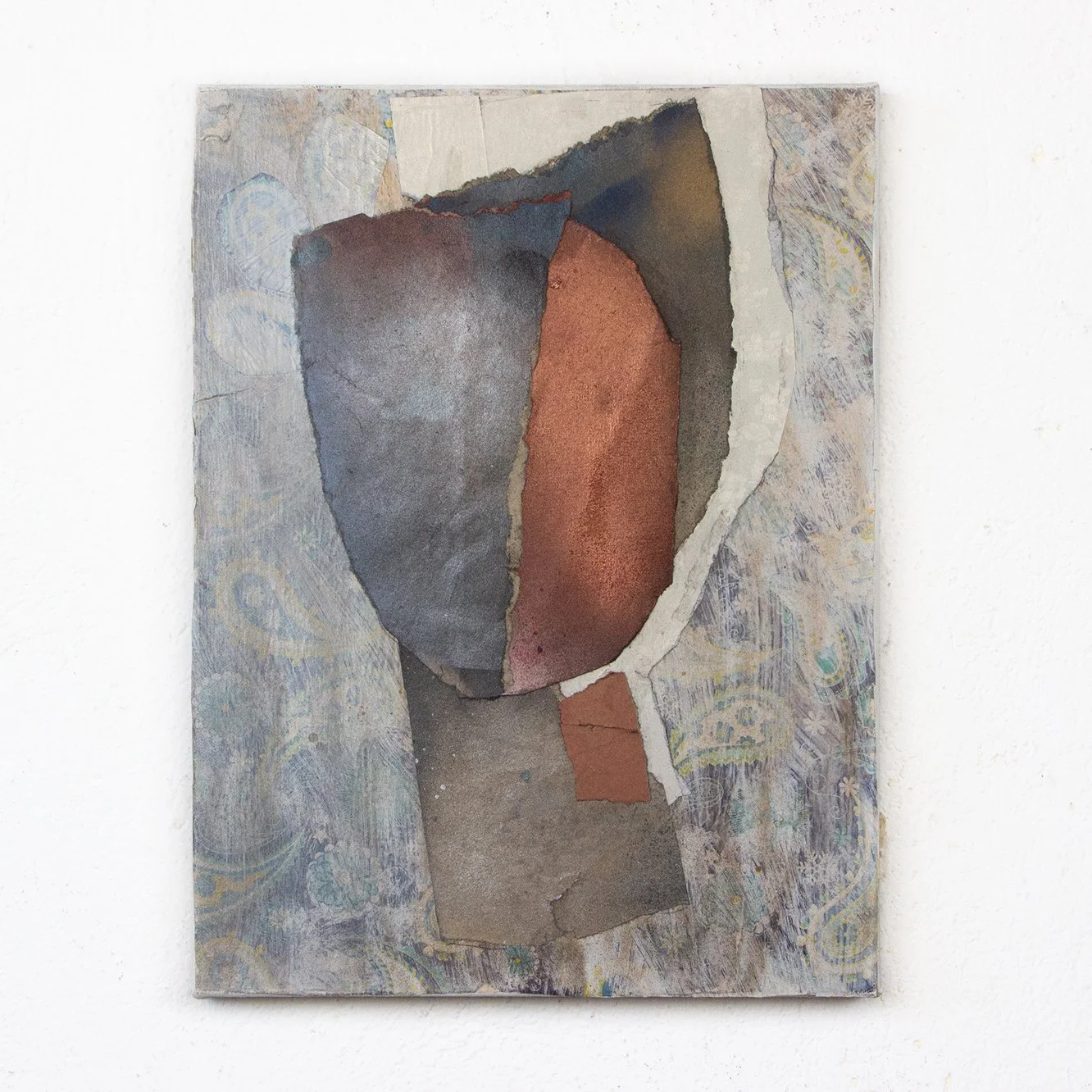 Mixed media artwork with torn paper in abstract shapes and muted earth tones, mounted on a white wall.