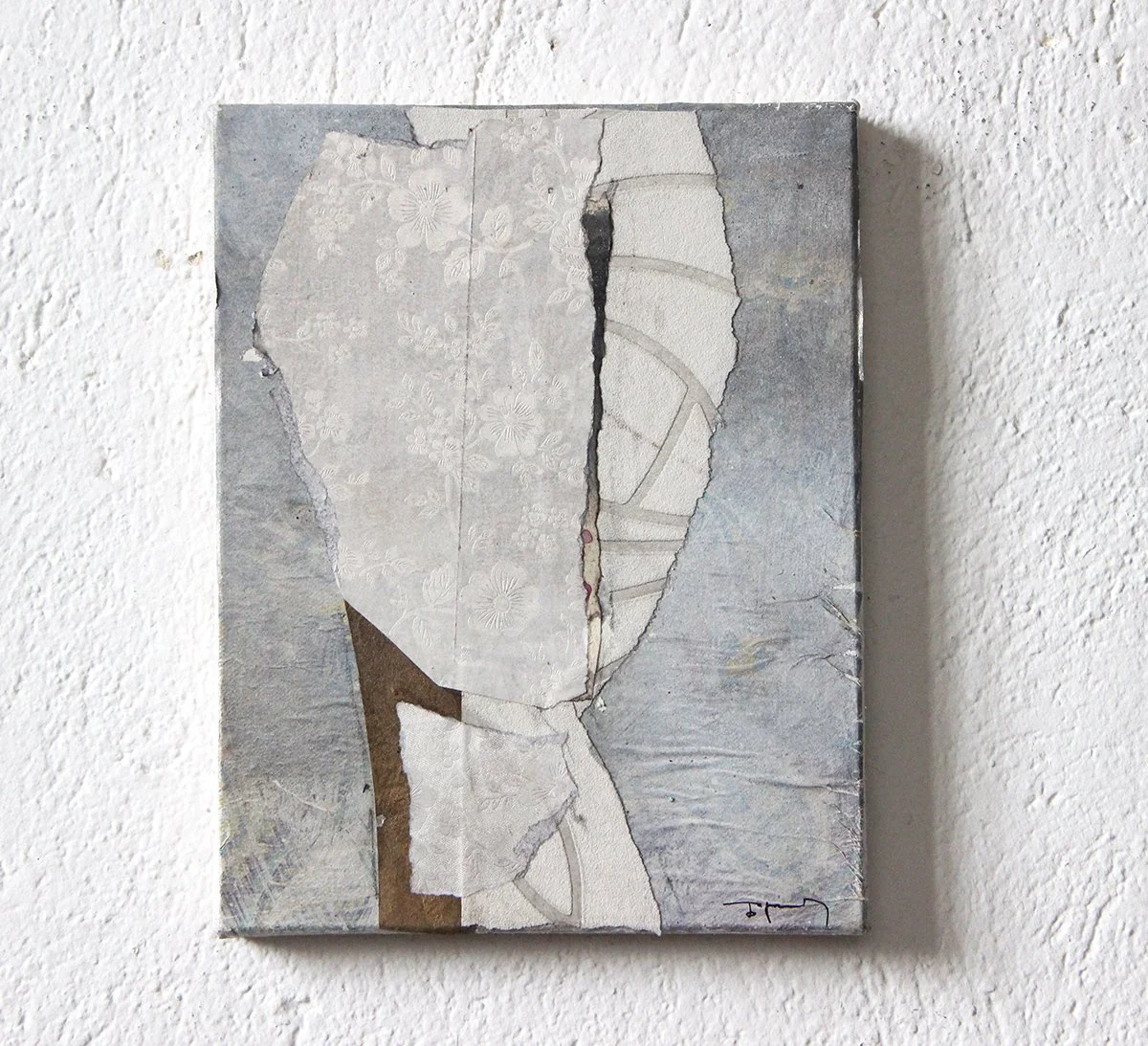 contemporary abstract collage artwork combining torn paper with floral and geometric patterns on a textured wall.