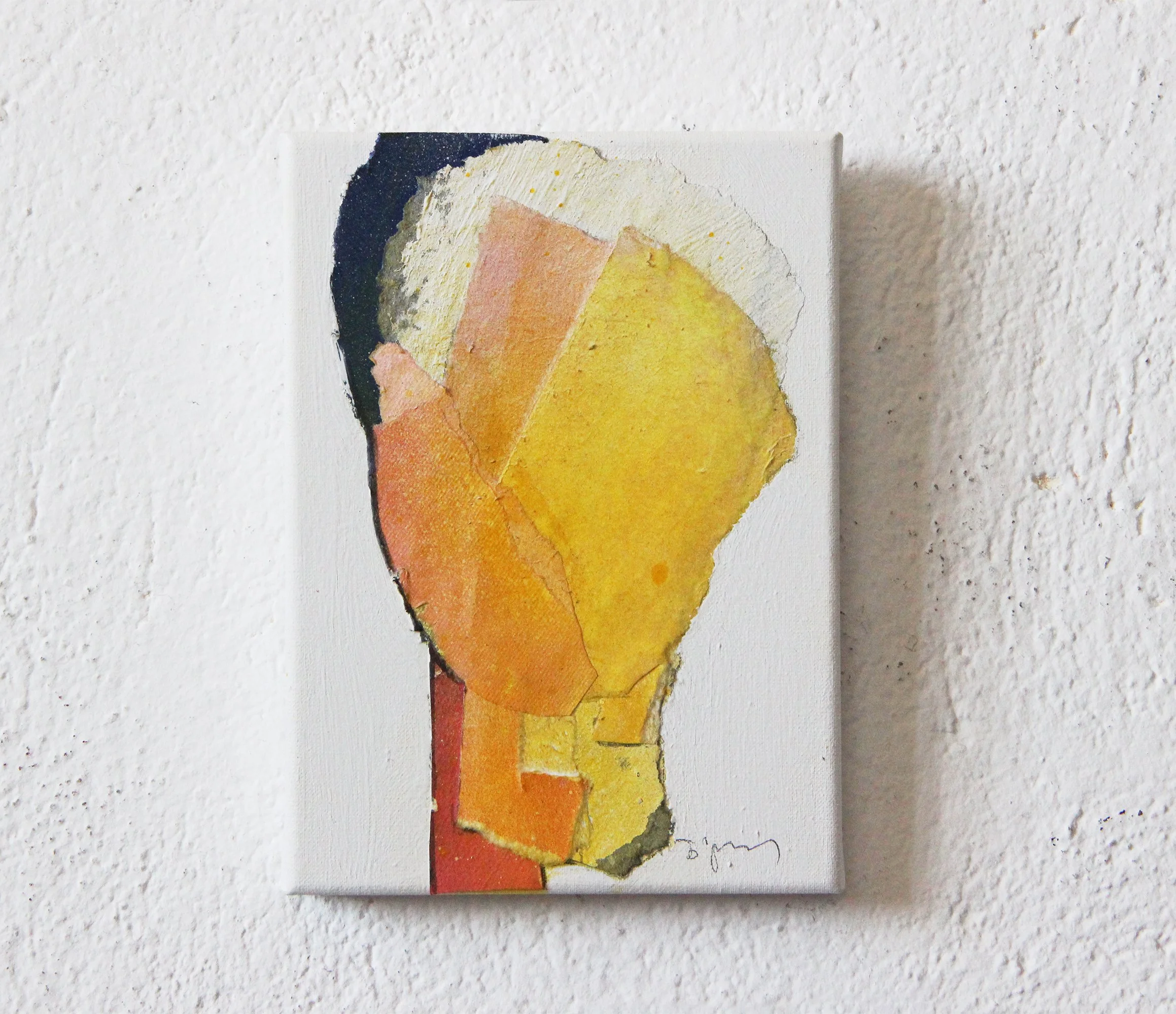 Abstract watercolor painting on a small canvas, featuring geometric shapes in shades of yellow, orange, pink, beige, and black, mounted on a textured white wall.