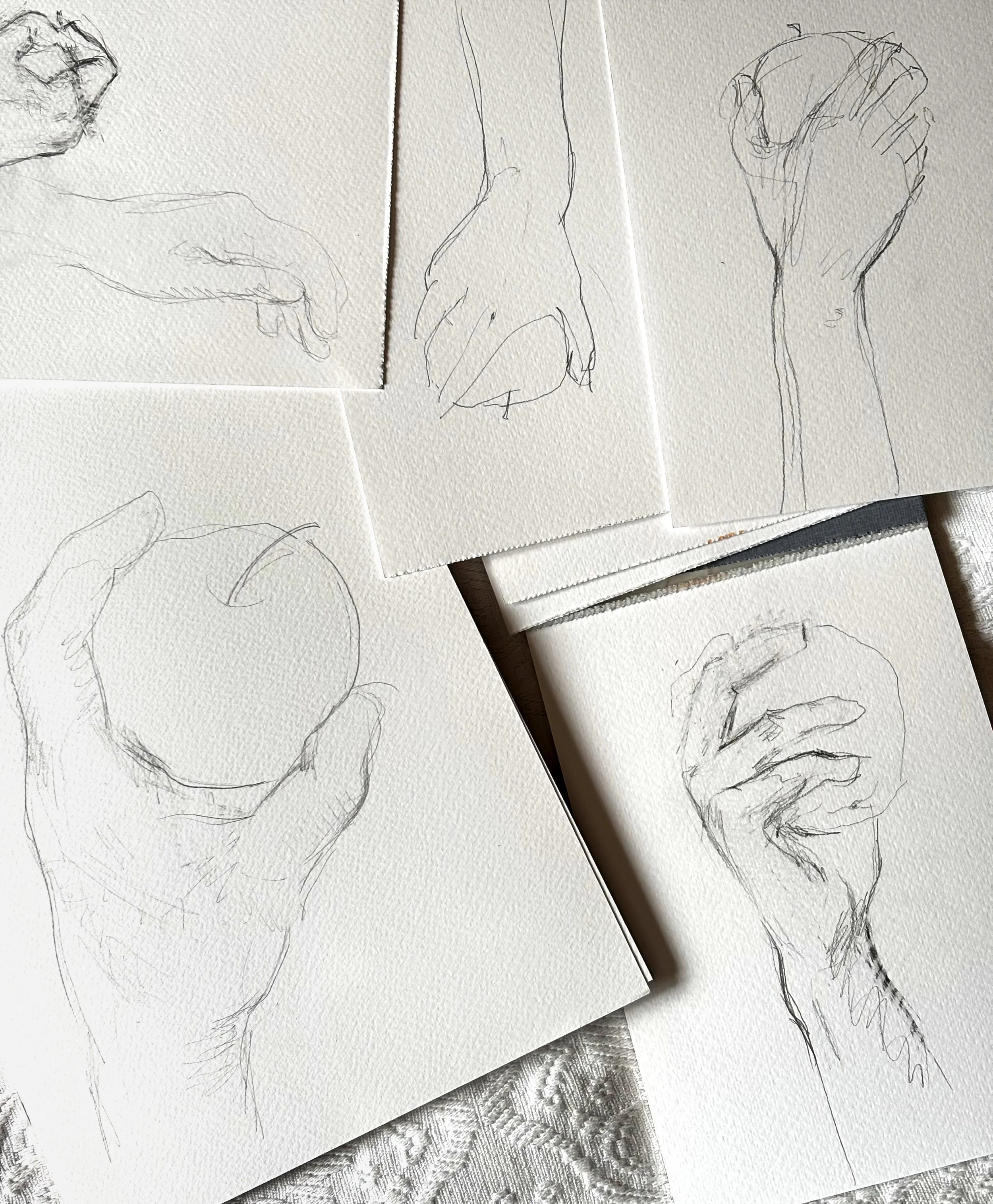 Series of small sketches in pencil on white paper showing hands in different positions—holding an apple, a fist, a hand with fingers curled, and a hand with fingers spread.