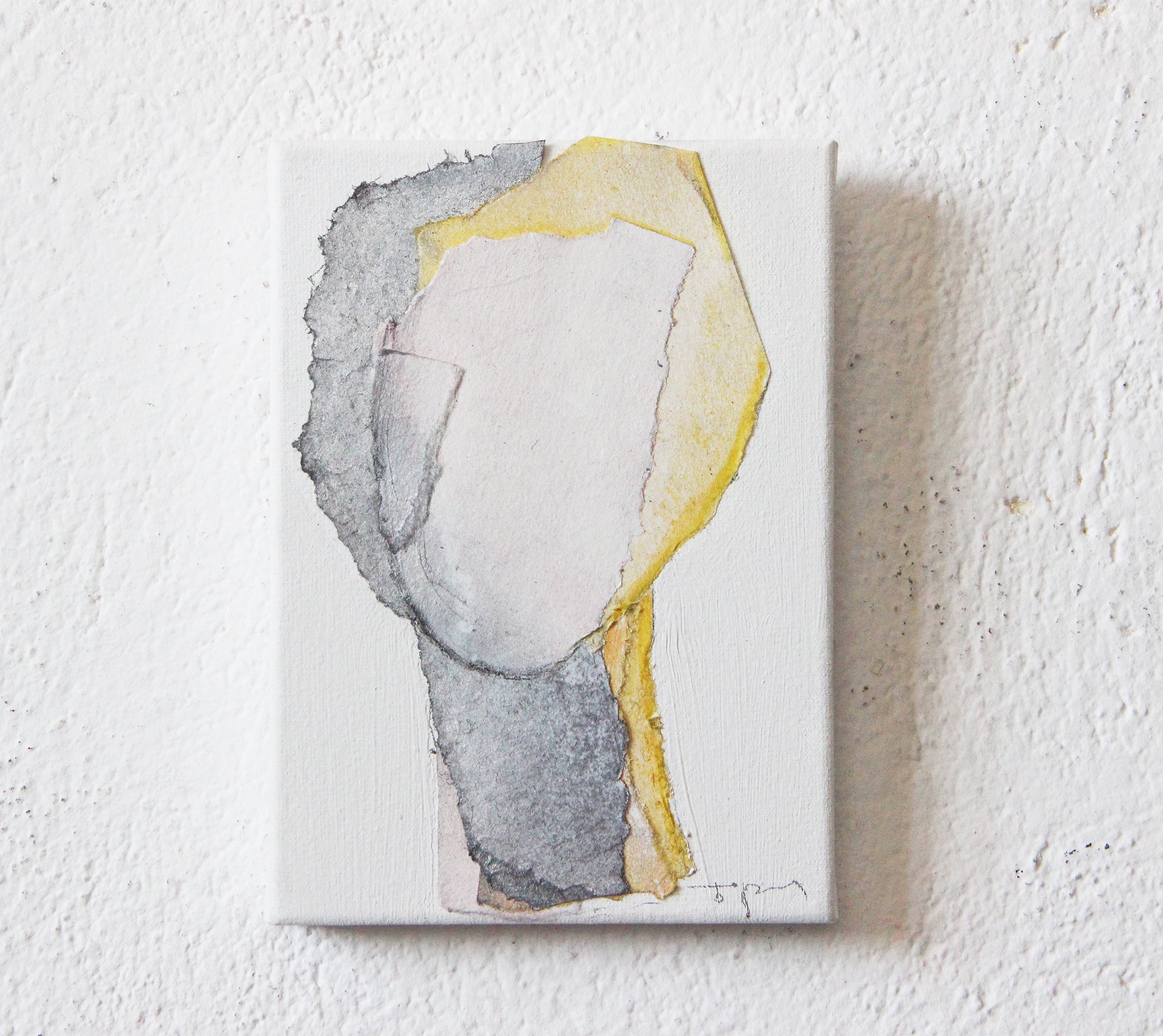 Abstract watercolor painting on a small canvas mounted on a white textured wall, featuring gray, yellow, and white shades.