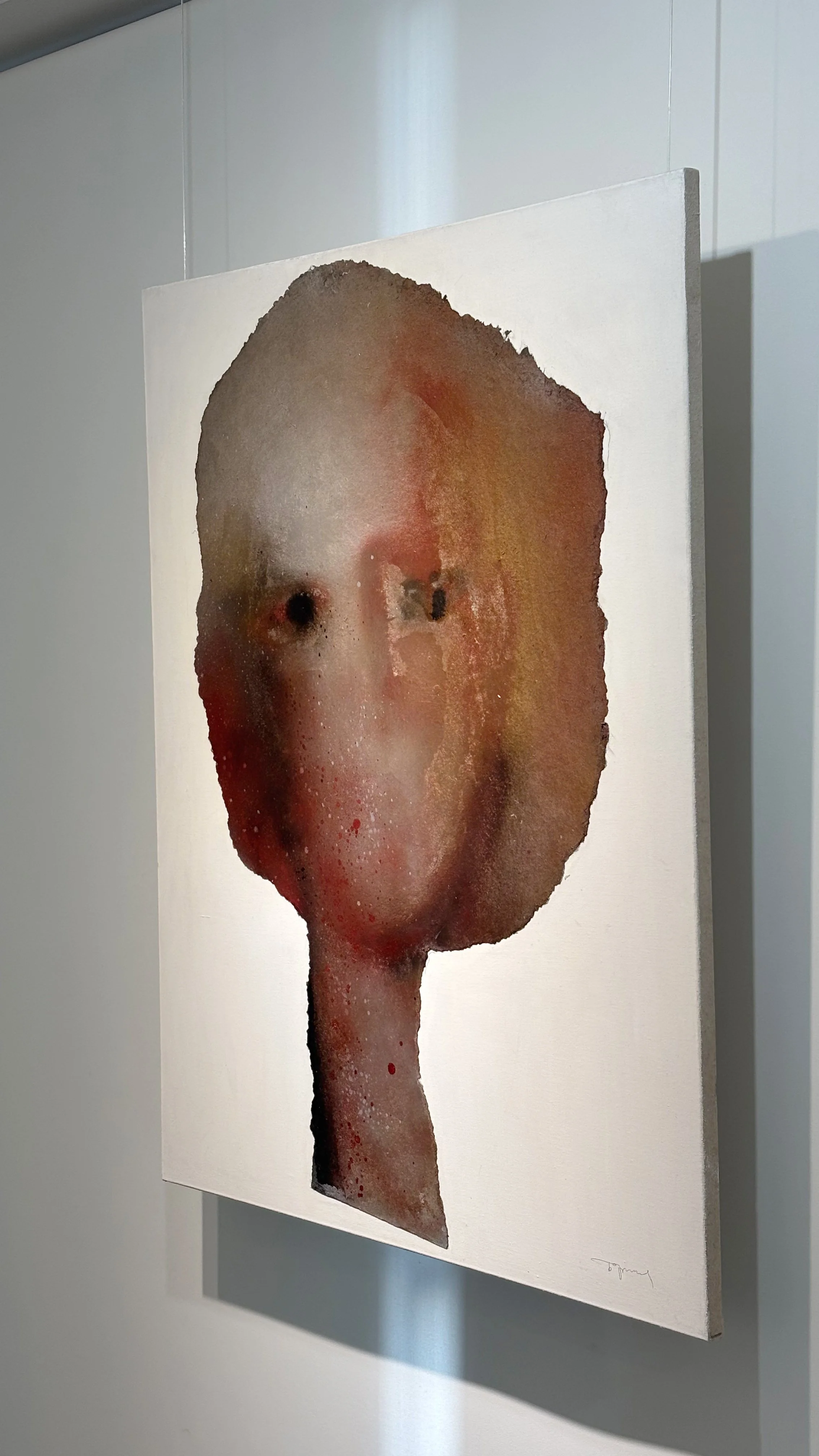 Abstract watercolor portrait of a face with elongated neck, featuring muted colors and minimal detail, displayed on a white wall.