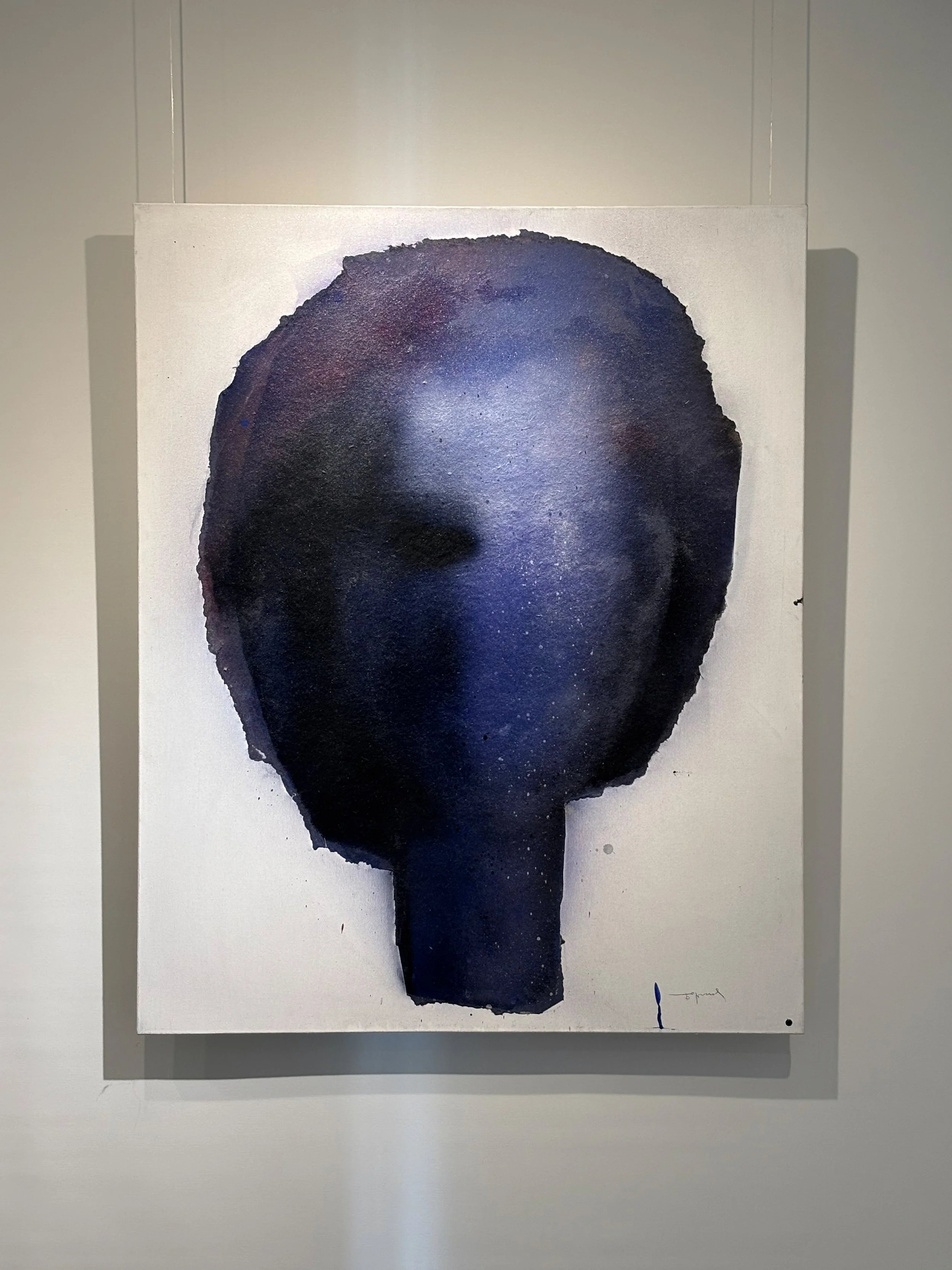 An abstract watercolor painting of a human face in dark blue and black tones on a white canvas.