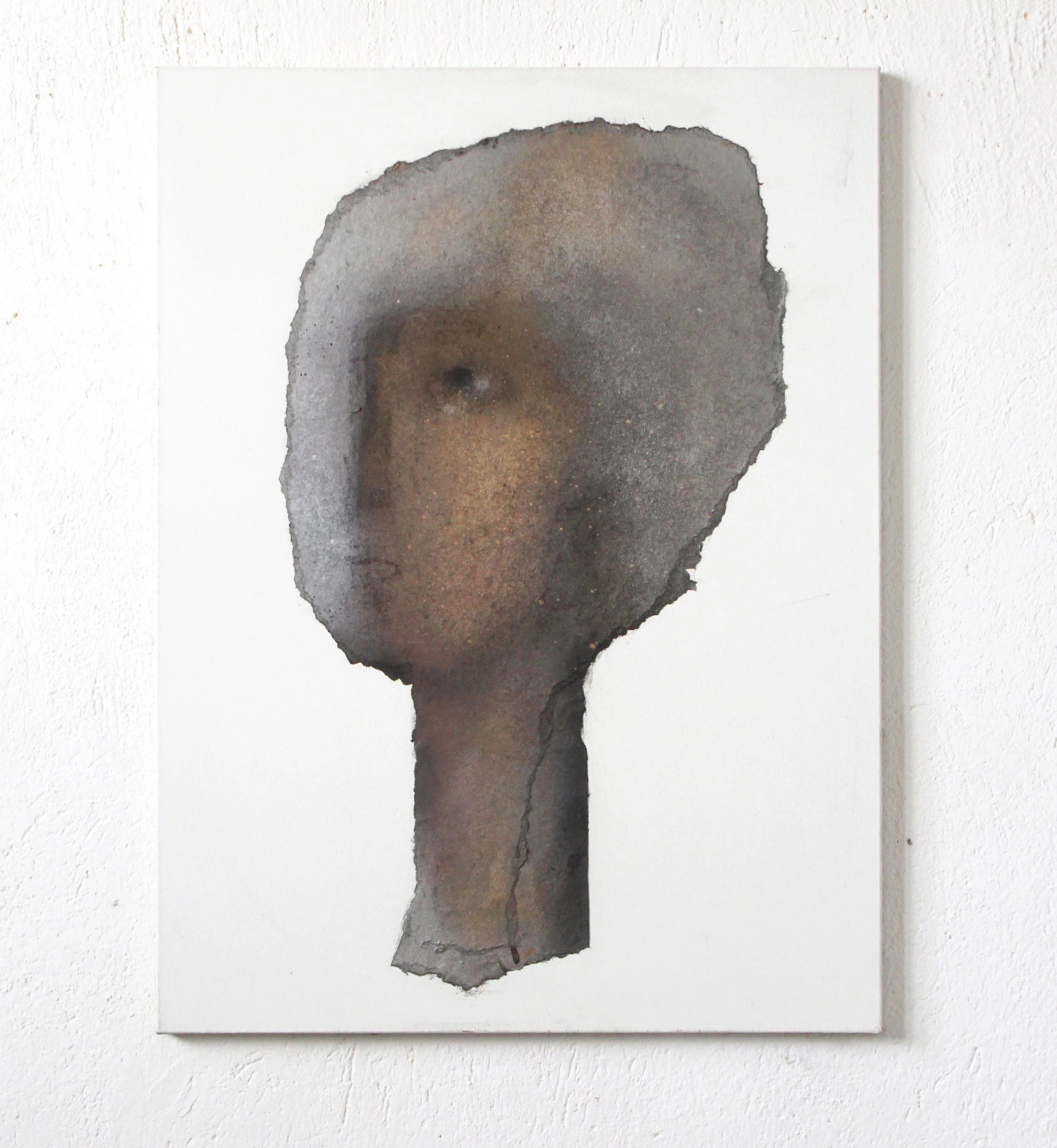 Abstract art piece resembling a human face with a dark, textured appearance, painted on a white canvas.