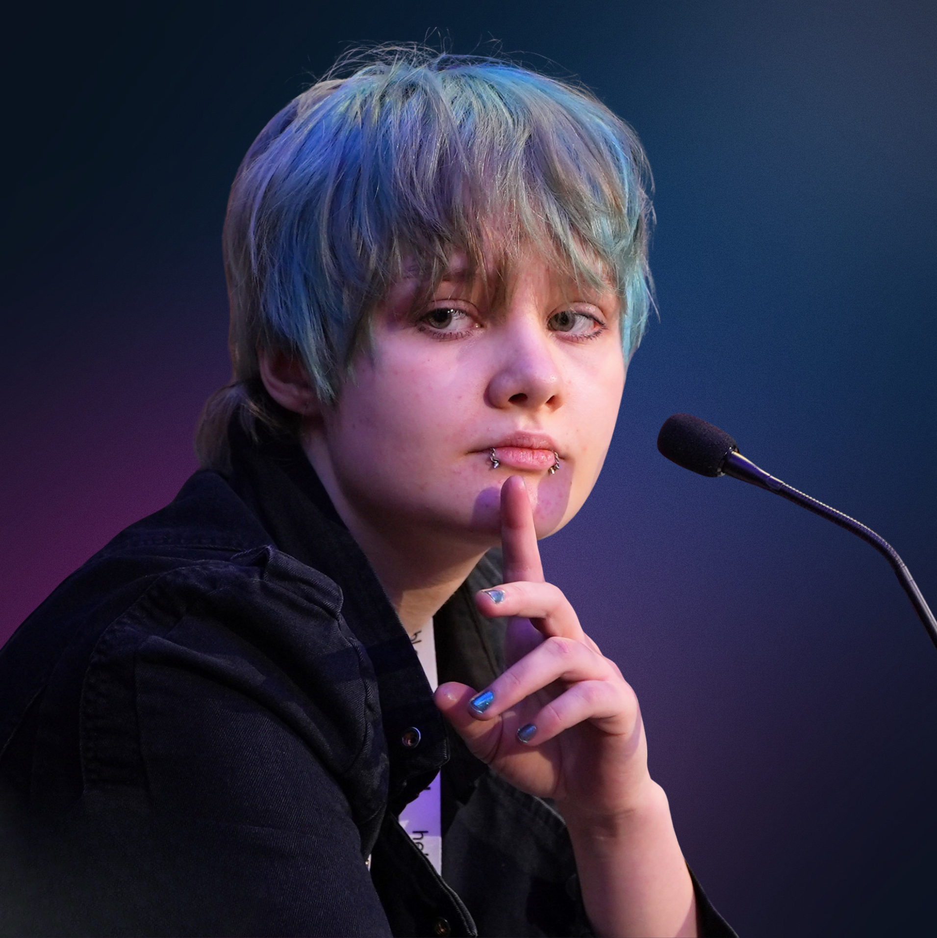 Close-up of Azi, trans-masc person with turquoise dyed short hair, holding a finger to their lips in a gesture of silence, with a microphone nearby.