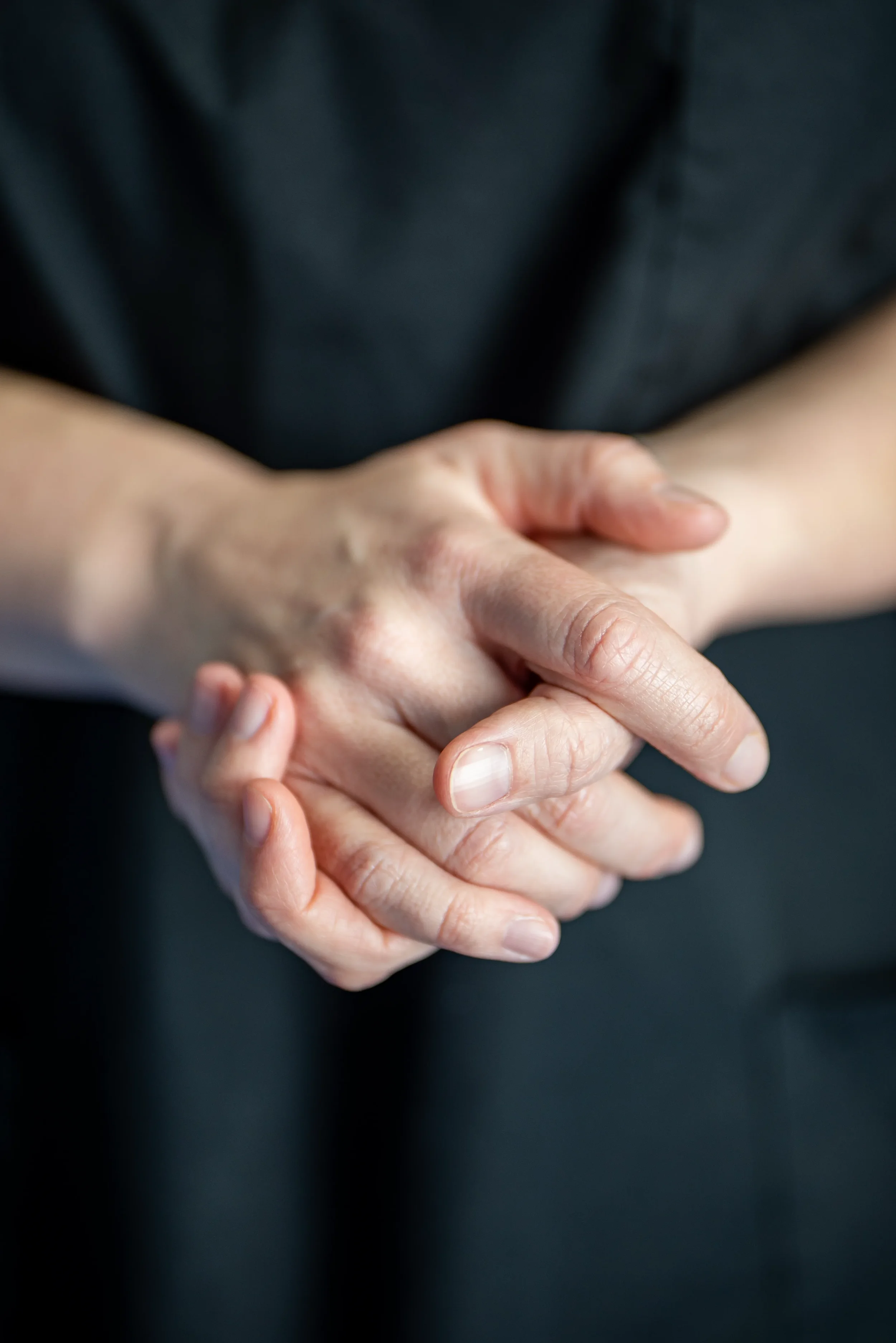 Close-up of two people holding hands, with one hand gripping the other in a gentle clasp.